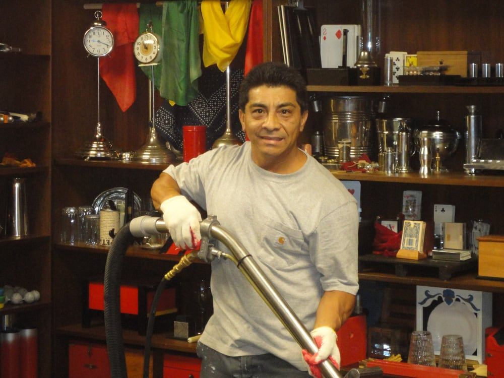 A man in a grey shirt is holding a vacuum cleaner