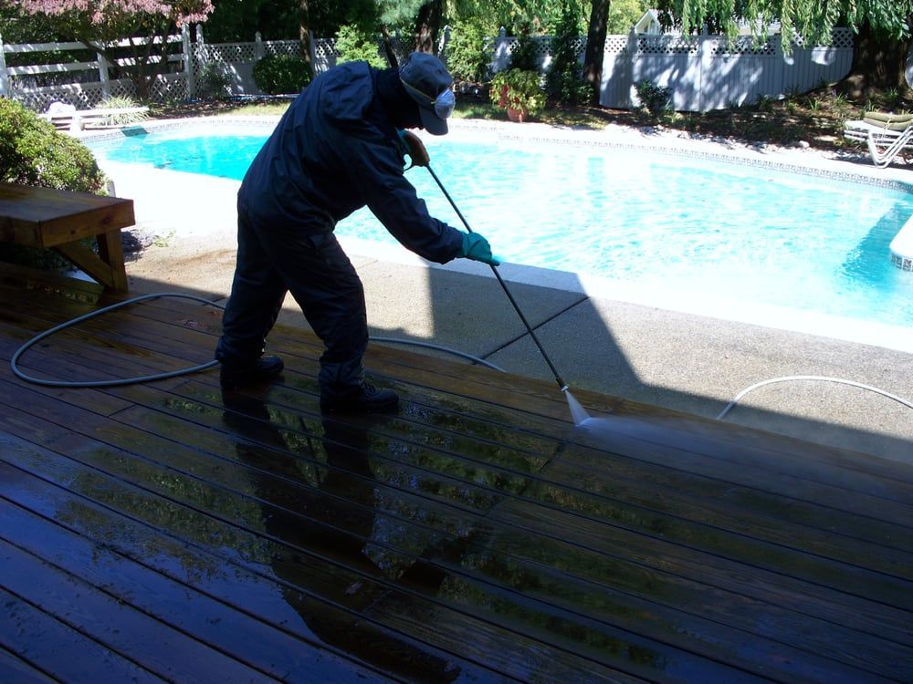 A man is cleaning a deck next to a pool