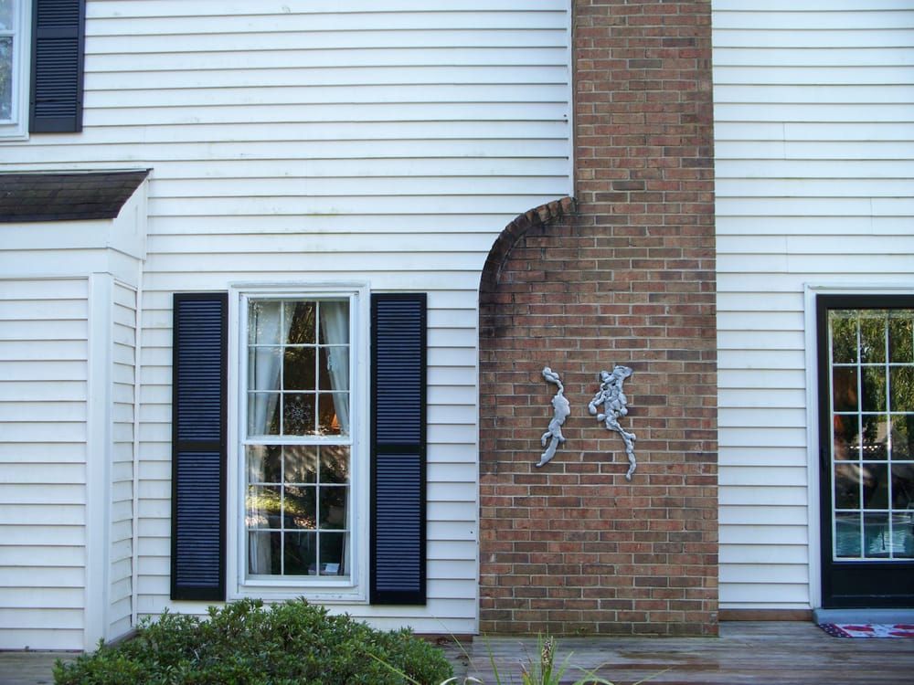 A white house with black shutters and a brick chimney