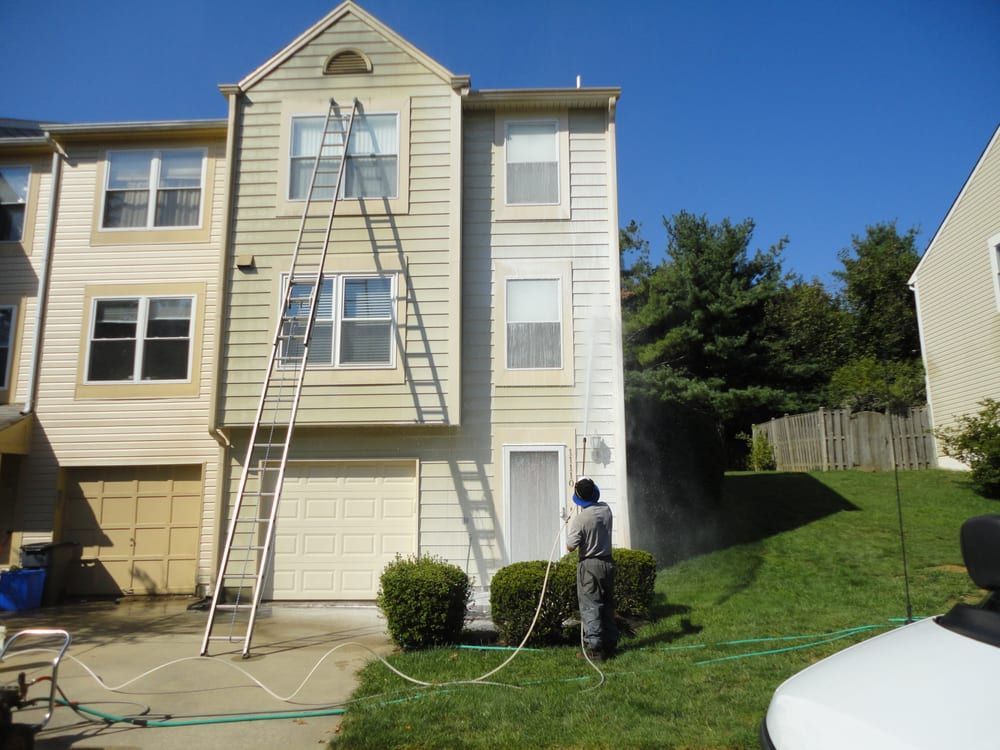 A man is cleaning the outside of a house with a ladder