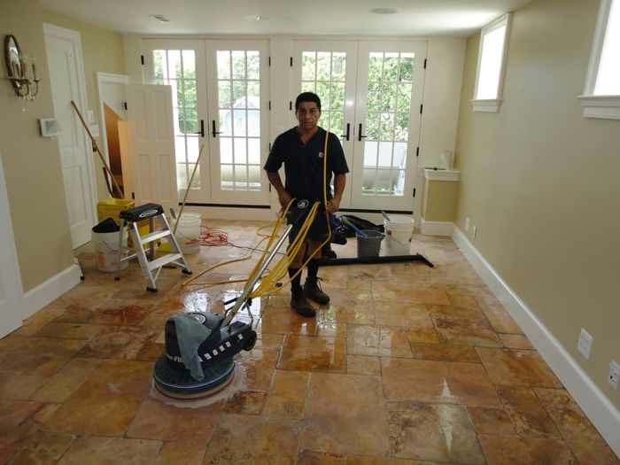 A man is polishing a tile floor with a machine