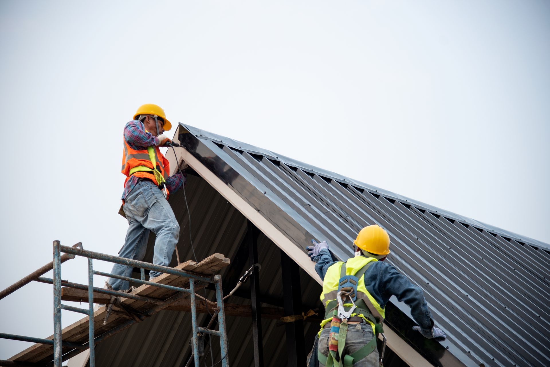 Roofing workers installing a metal roof on a building