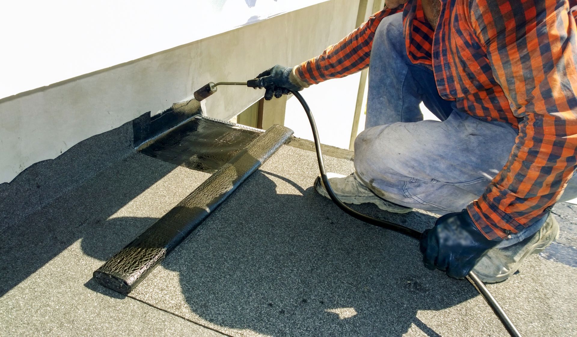 A roofer is preparing part of a bitumen roofing.