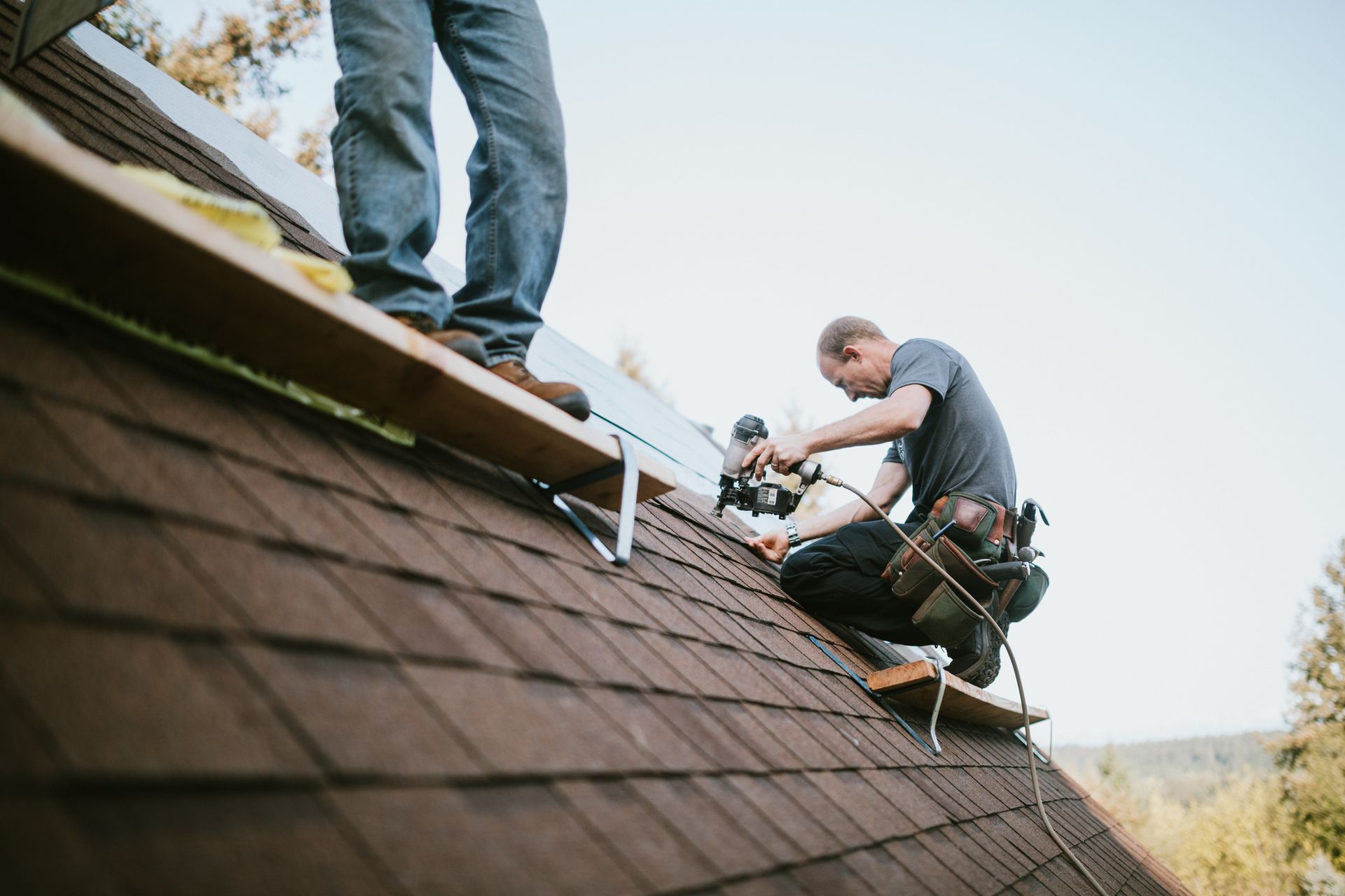 Two residential roofing contractors are putting in new roofing shingles. Two residential roofing contractors are putting in new roofing shingles.