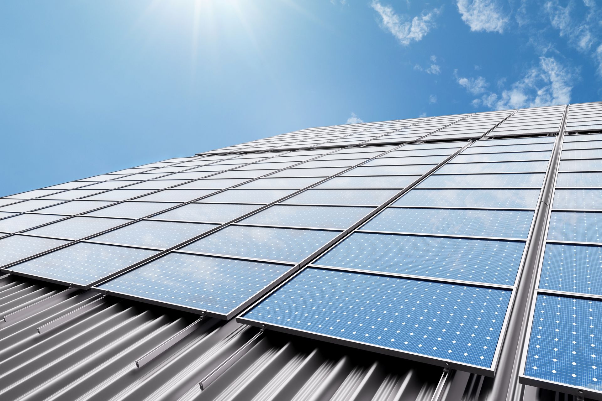 Solar panels on a corrugated metal roof under a sunny blue sky.