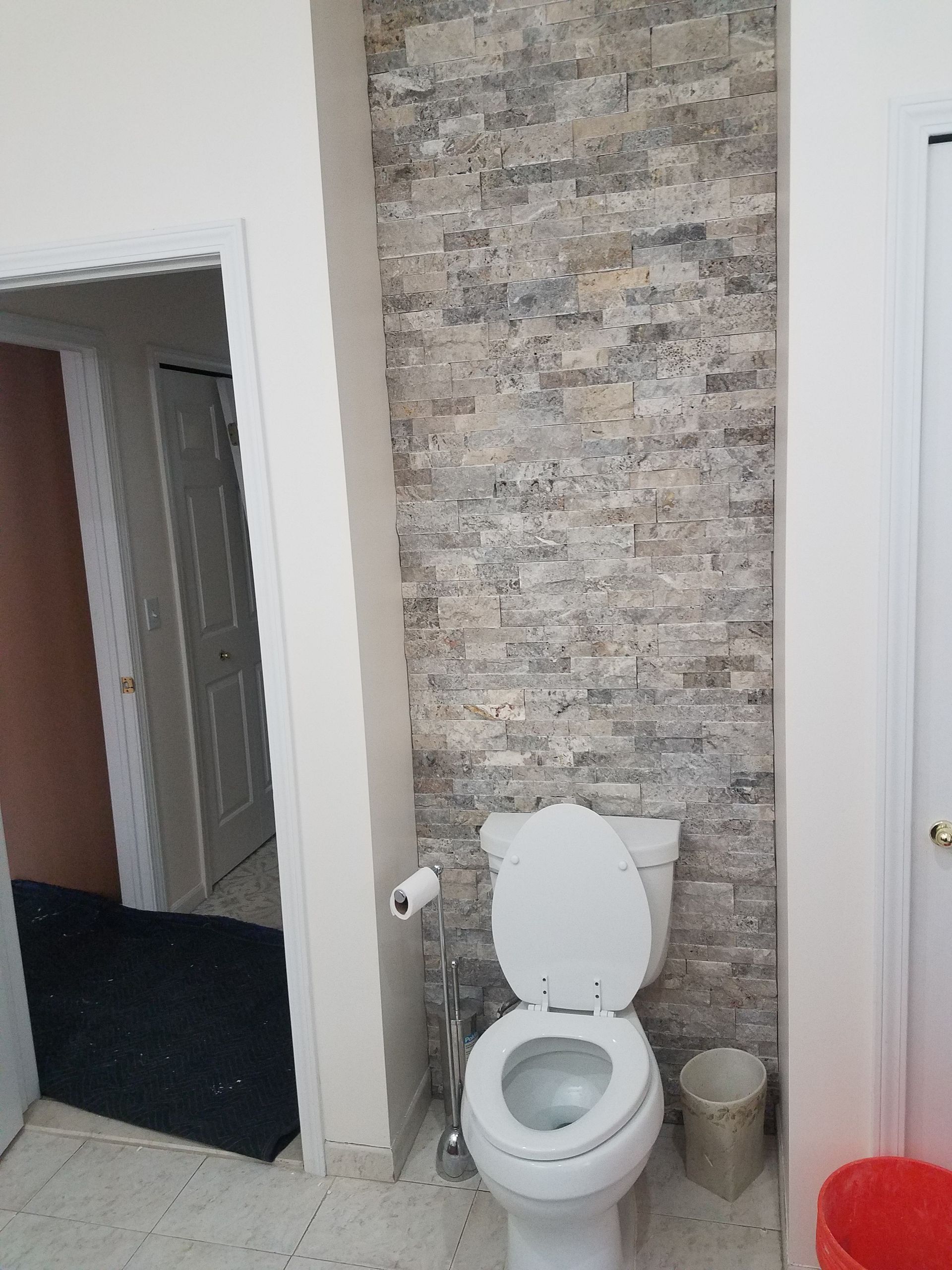 A bathroom with a toilet and a trash can
