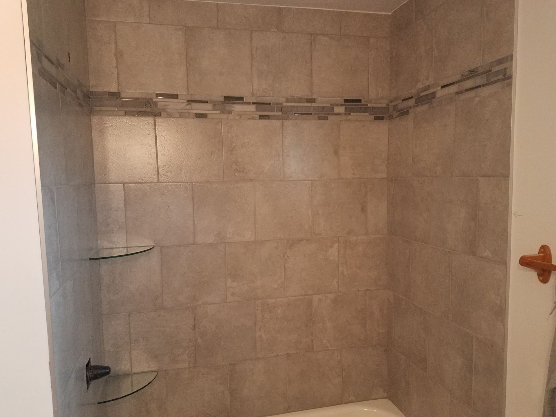 A bathroom with a tub and a shower with tiled walls.