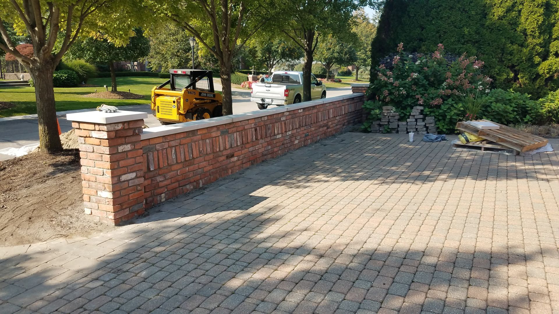 A brick wall is being built in a driveway.
