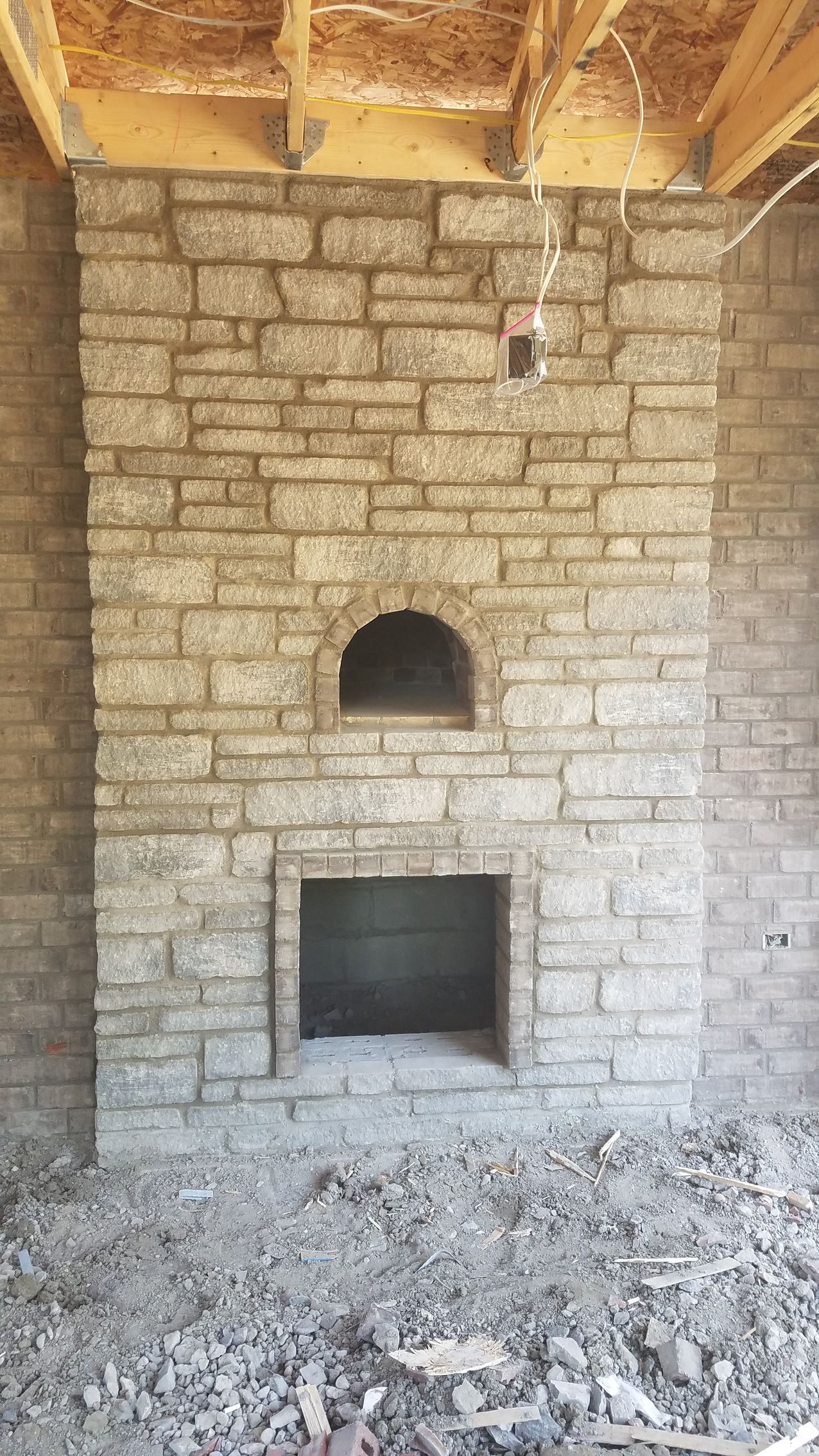 A brick fireplace with a hole in the middle of it.