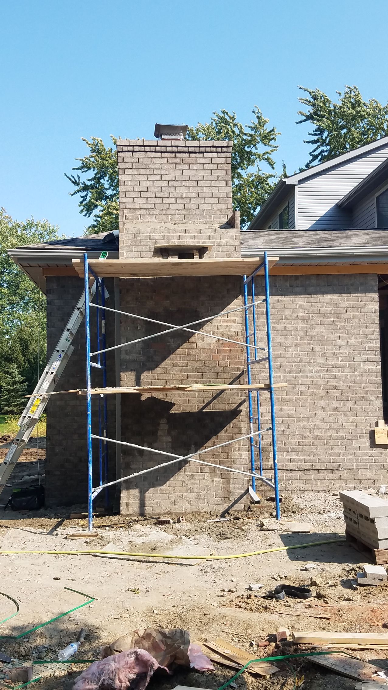 A brick chimney is being built on the side of a house.
