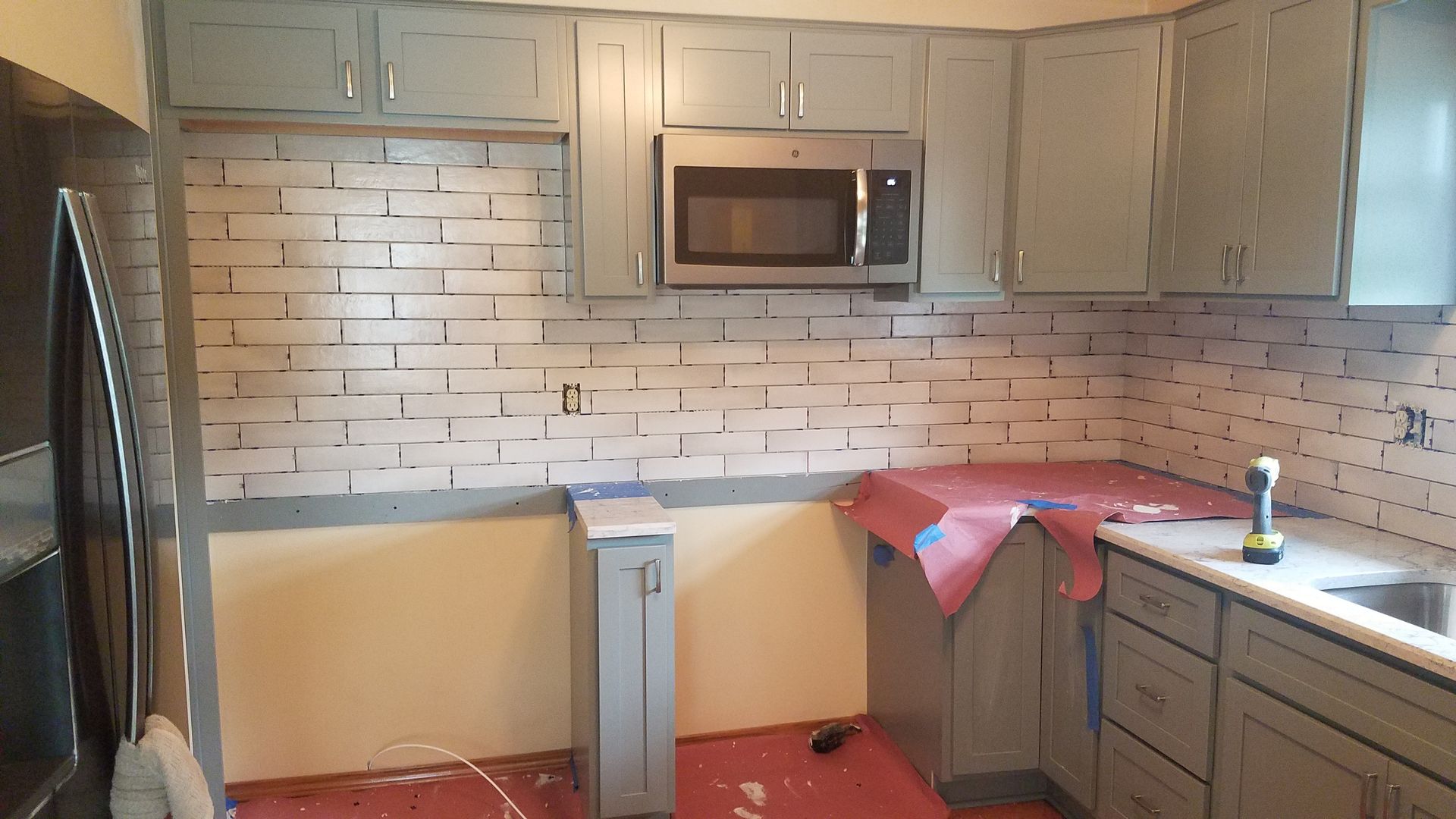 A kitchen with gray cabinets and a brick wall