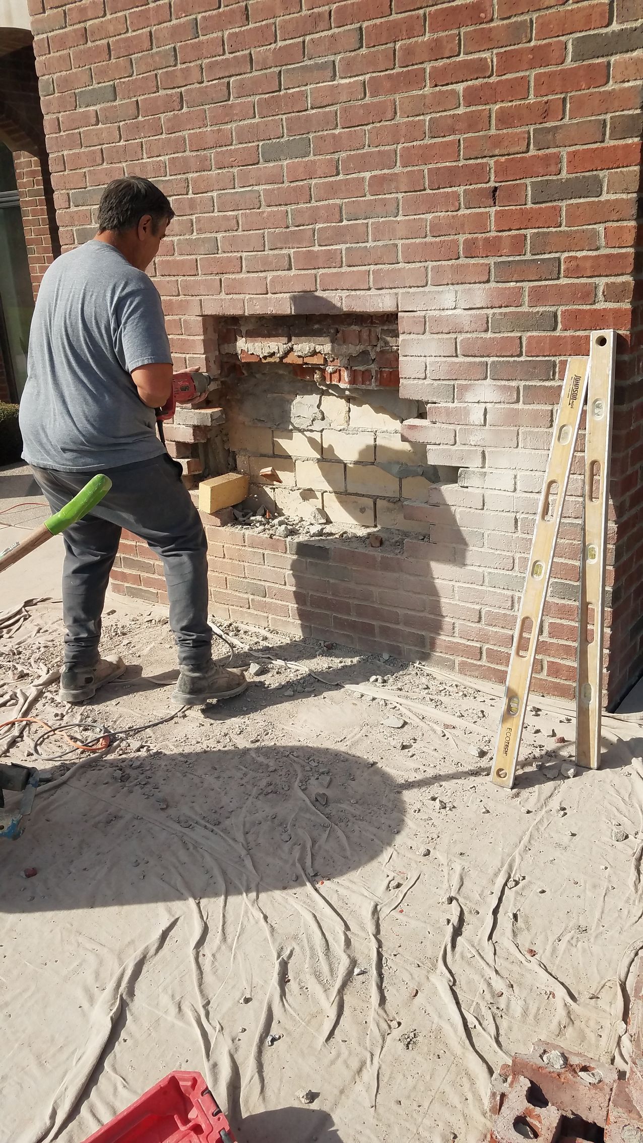 A man is working on a brick wall with a shovel.