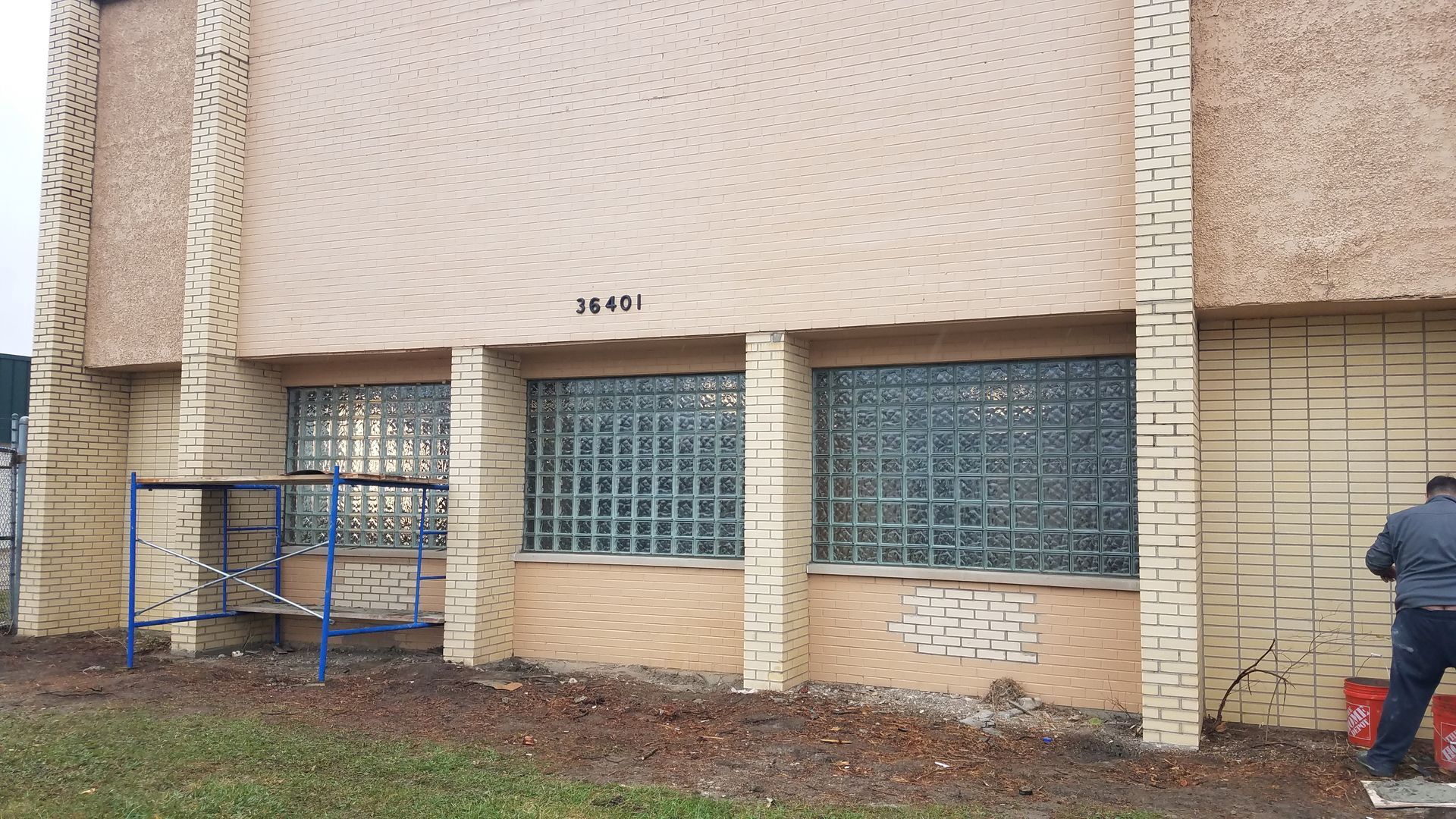 A man is standing in front of a building with the number 4618 on it