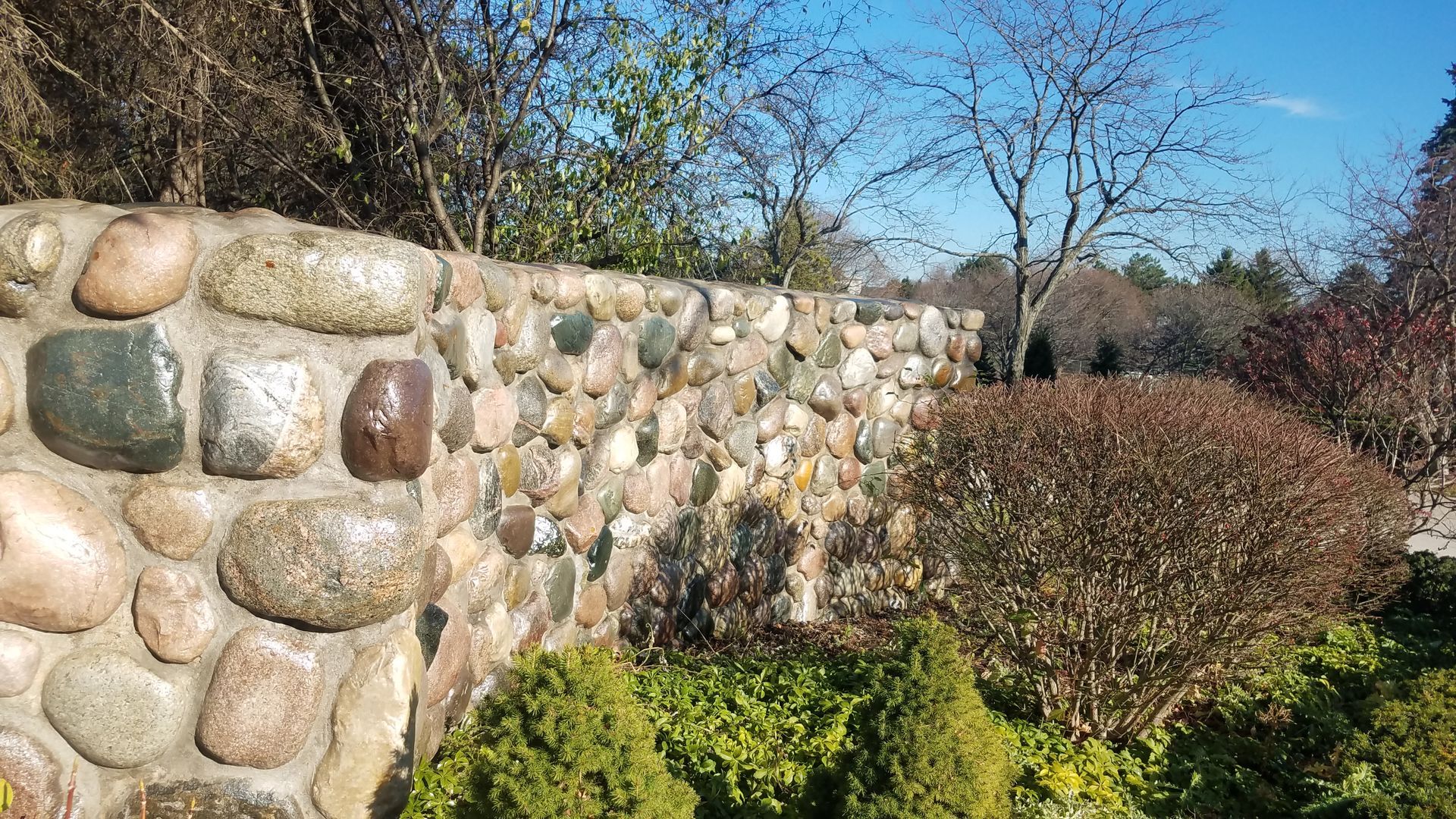 A stone wall in a garden with trees in the background