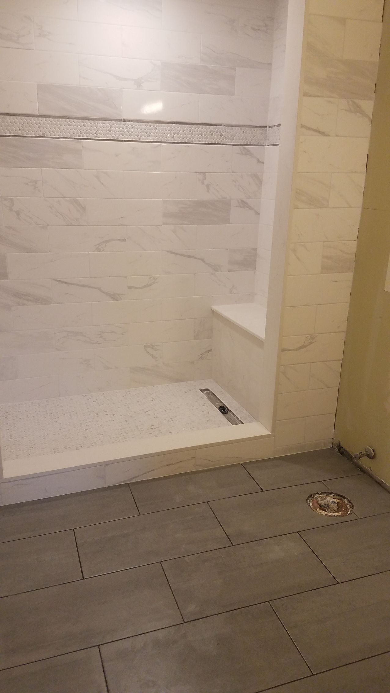 A bathroom with a walk in shower and a tiled floor.