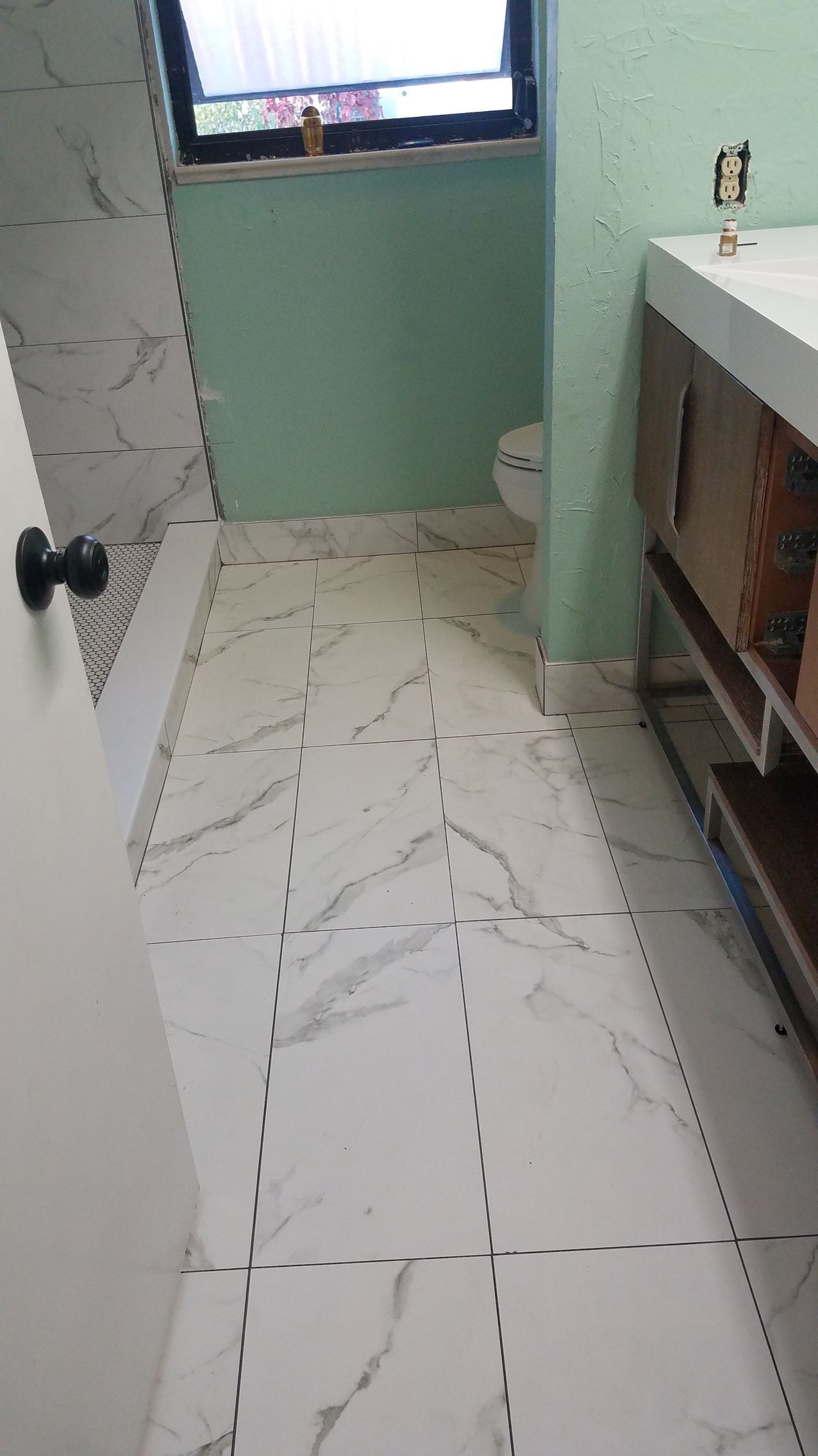 A bathroom with a toilet , sink , and window.