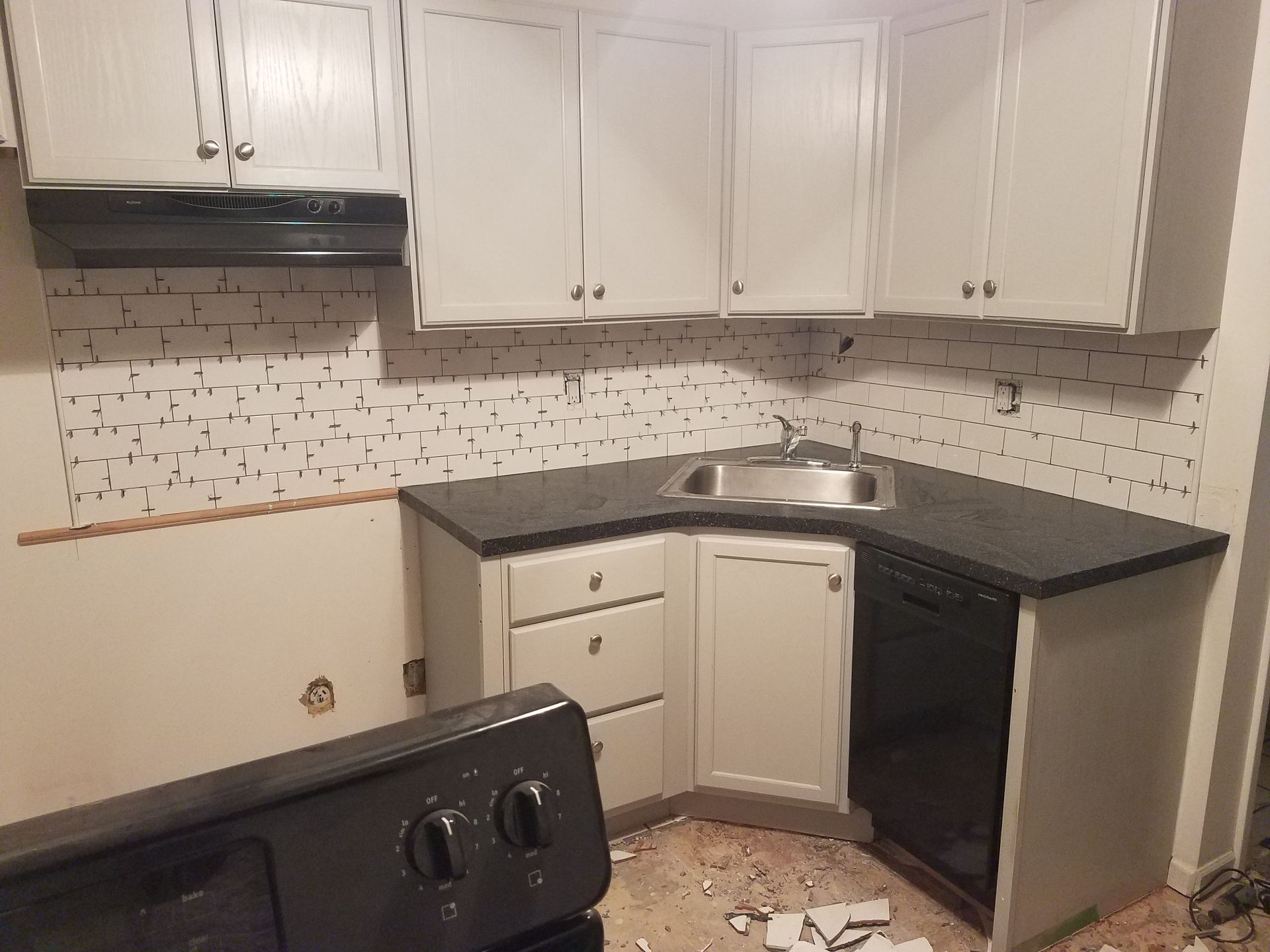 A kitchen with white cabinets and black counter tops