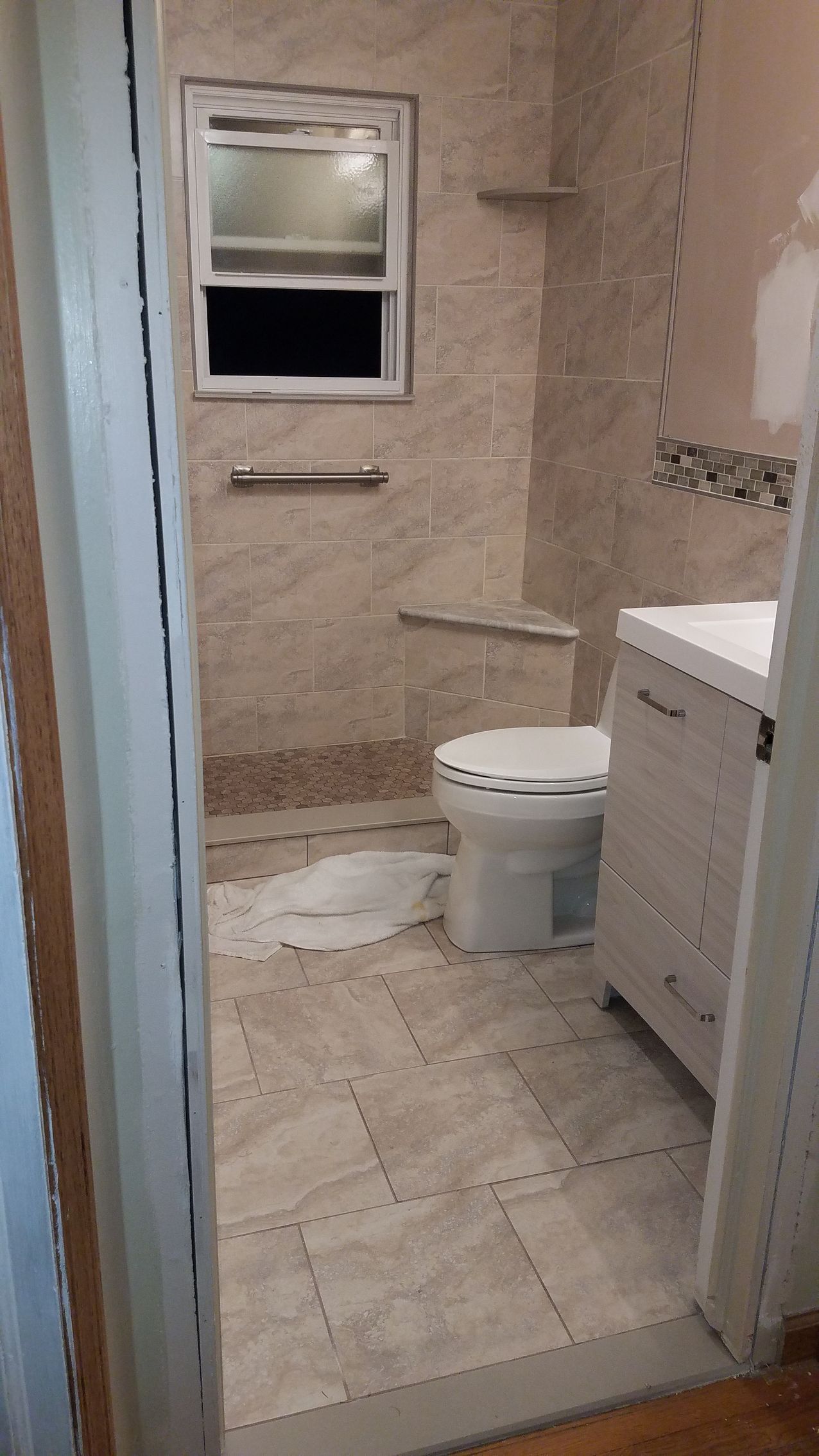 A bathroom with a toilet , sink , shower and window.