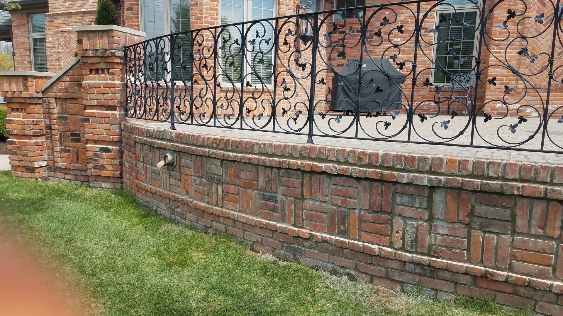A brick wall with a wrought iron fence around it.
