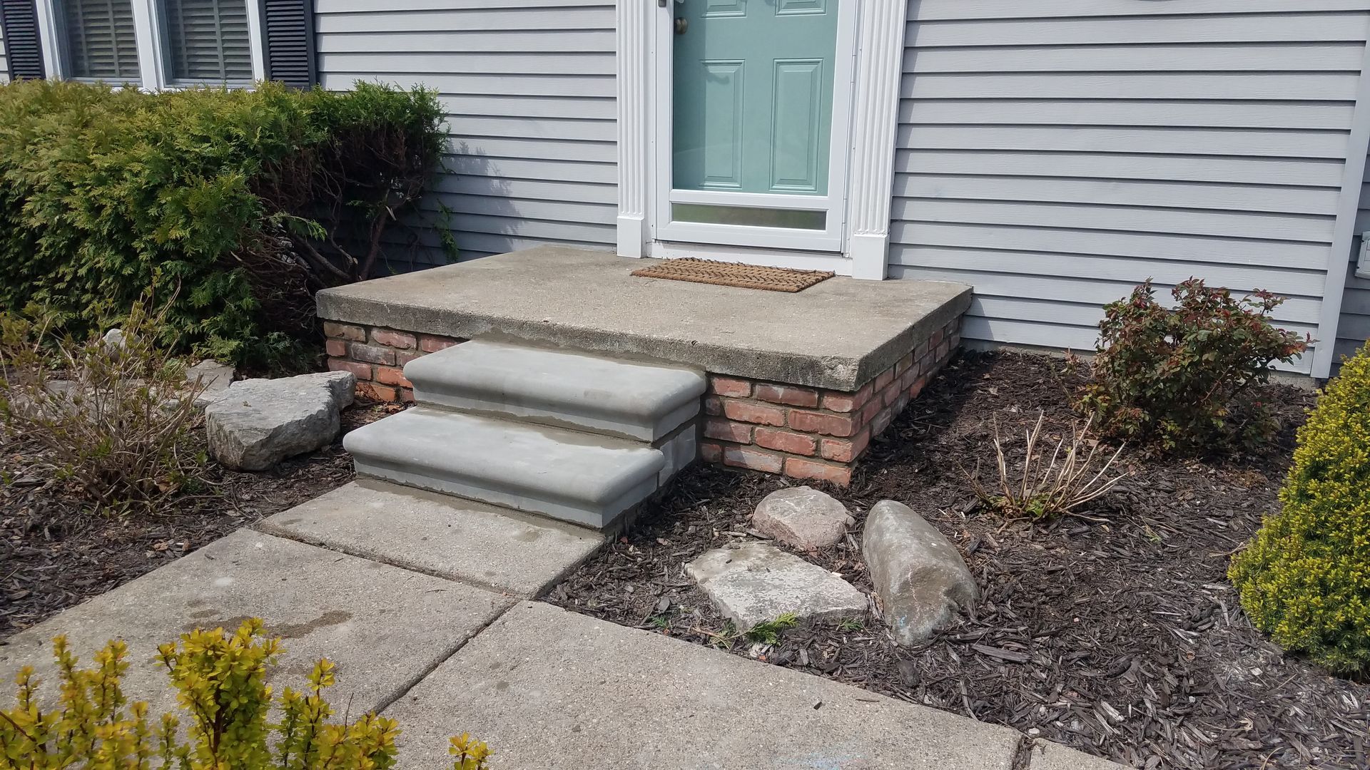 A concrete porch with steps leading to the front door of a house.