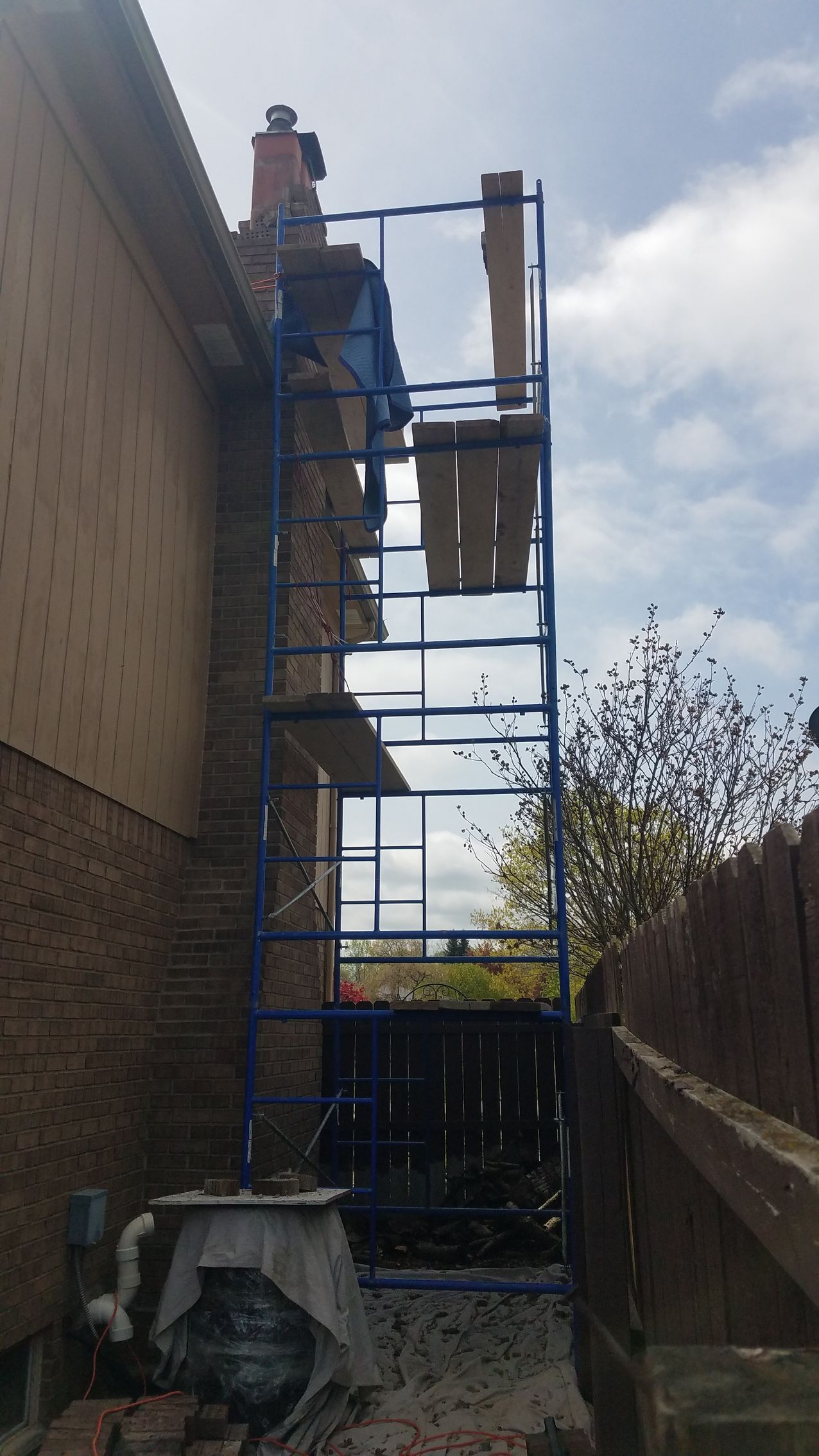 A blue scaffolding is attached to the side of a house.