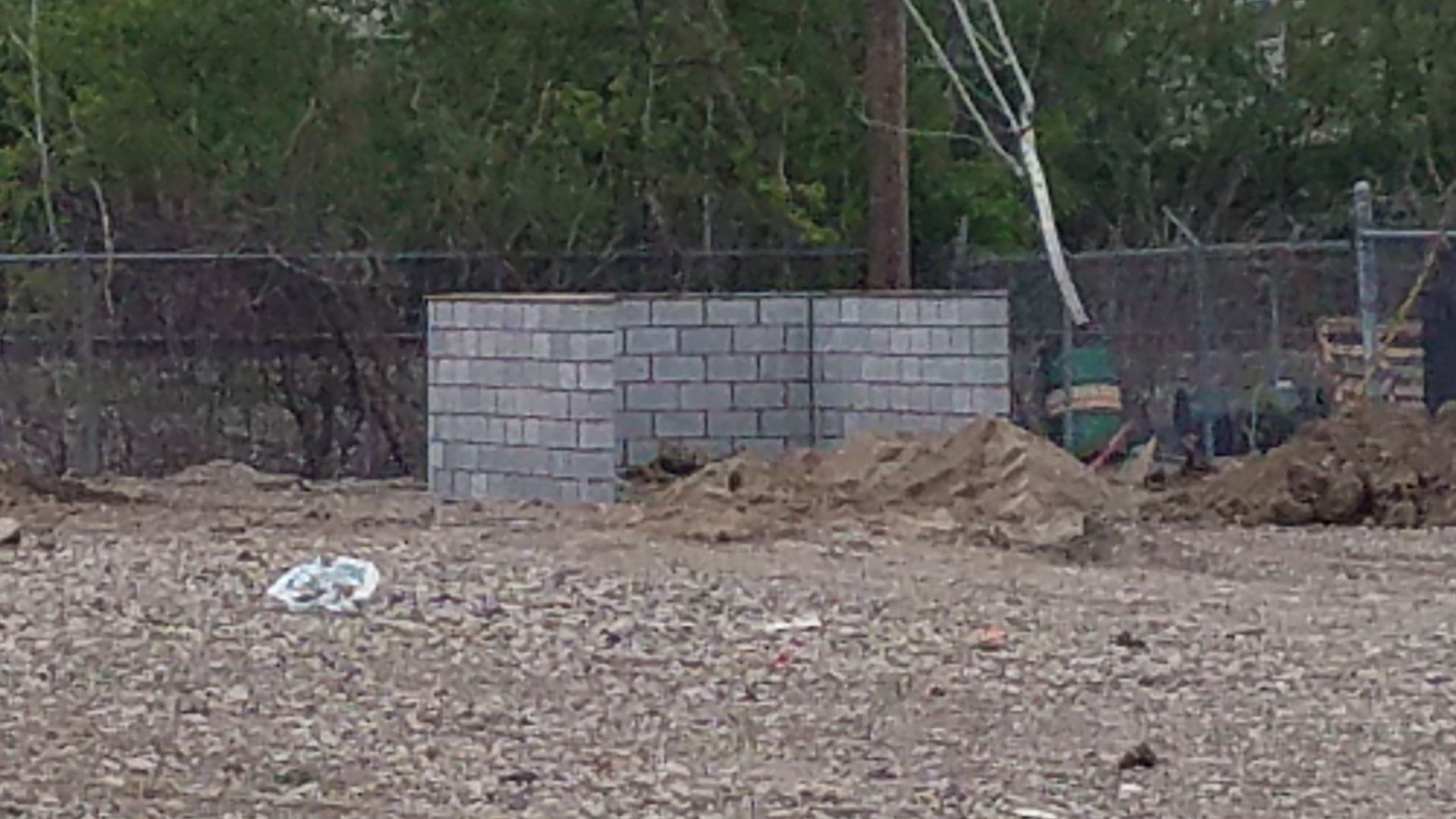 A brick wall is being built in a dirt field.