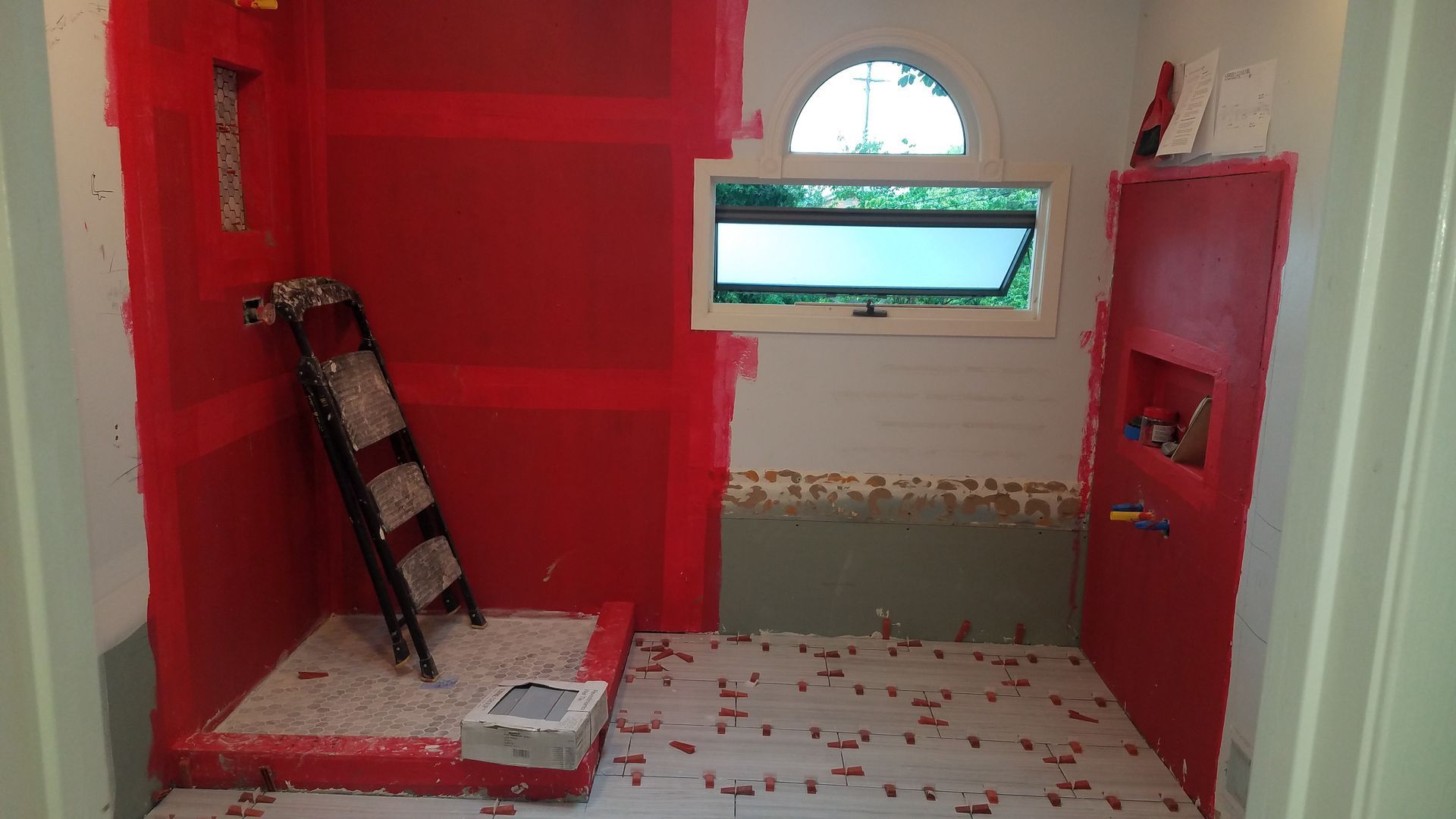 A bathroom with red walls and a ladder.