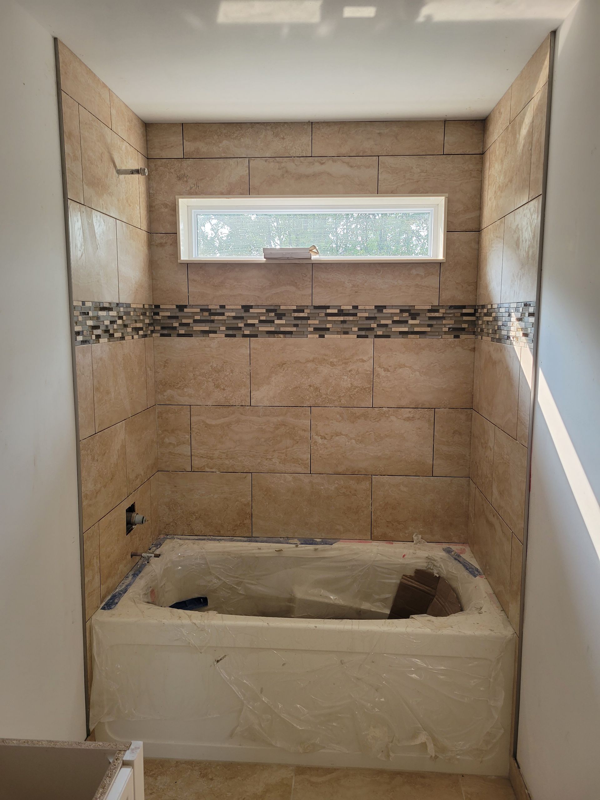A bathroom with a bathtub and a window.