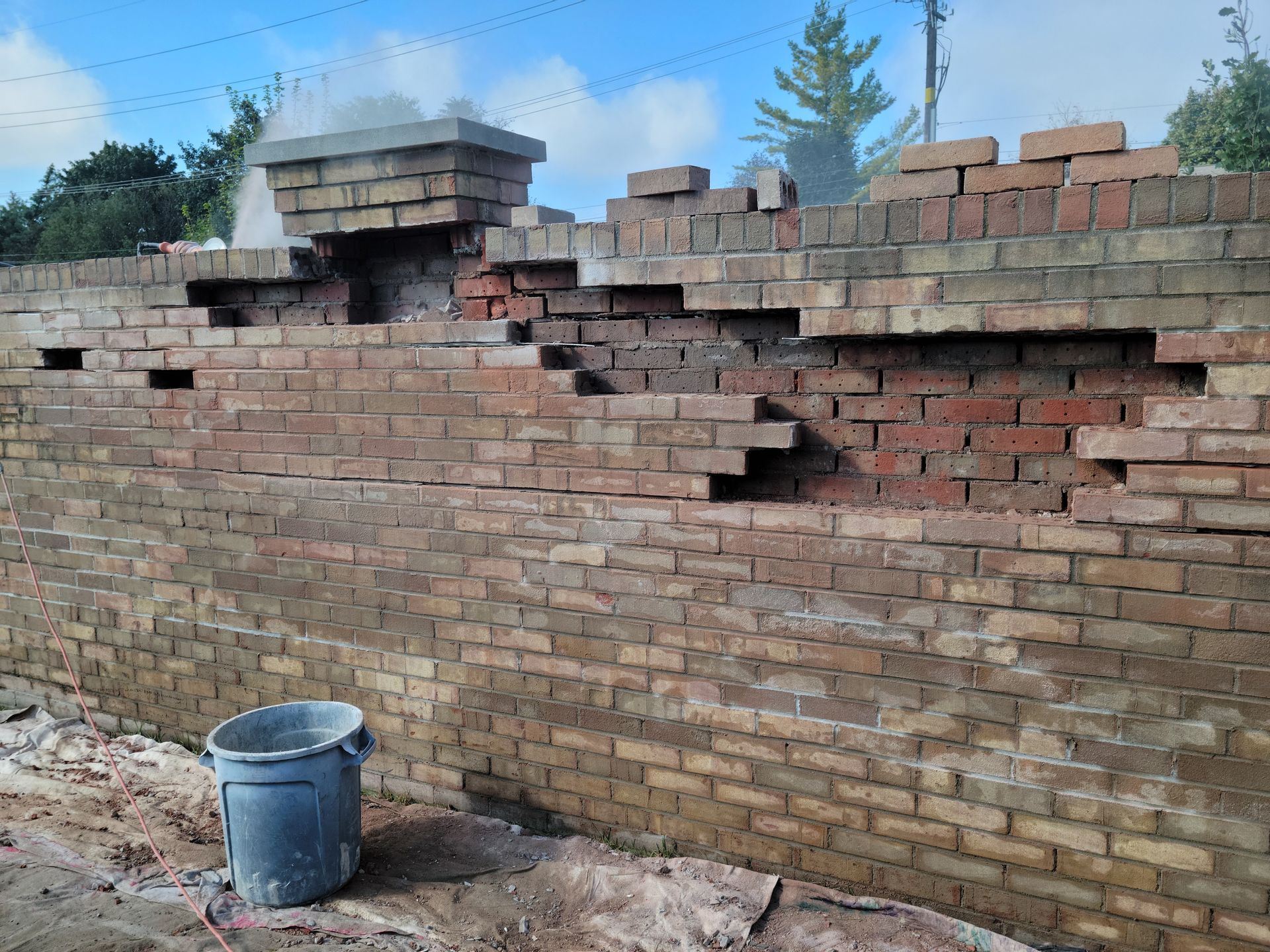 A bucket is sitting in front of a brick wall.