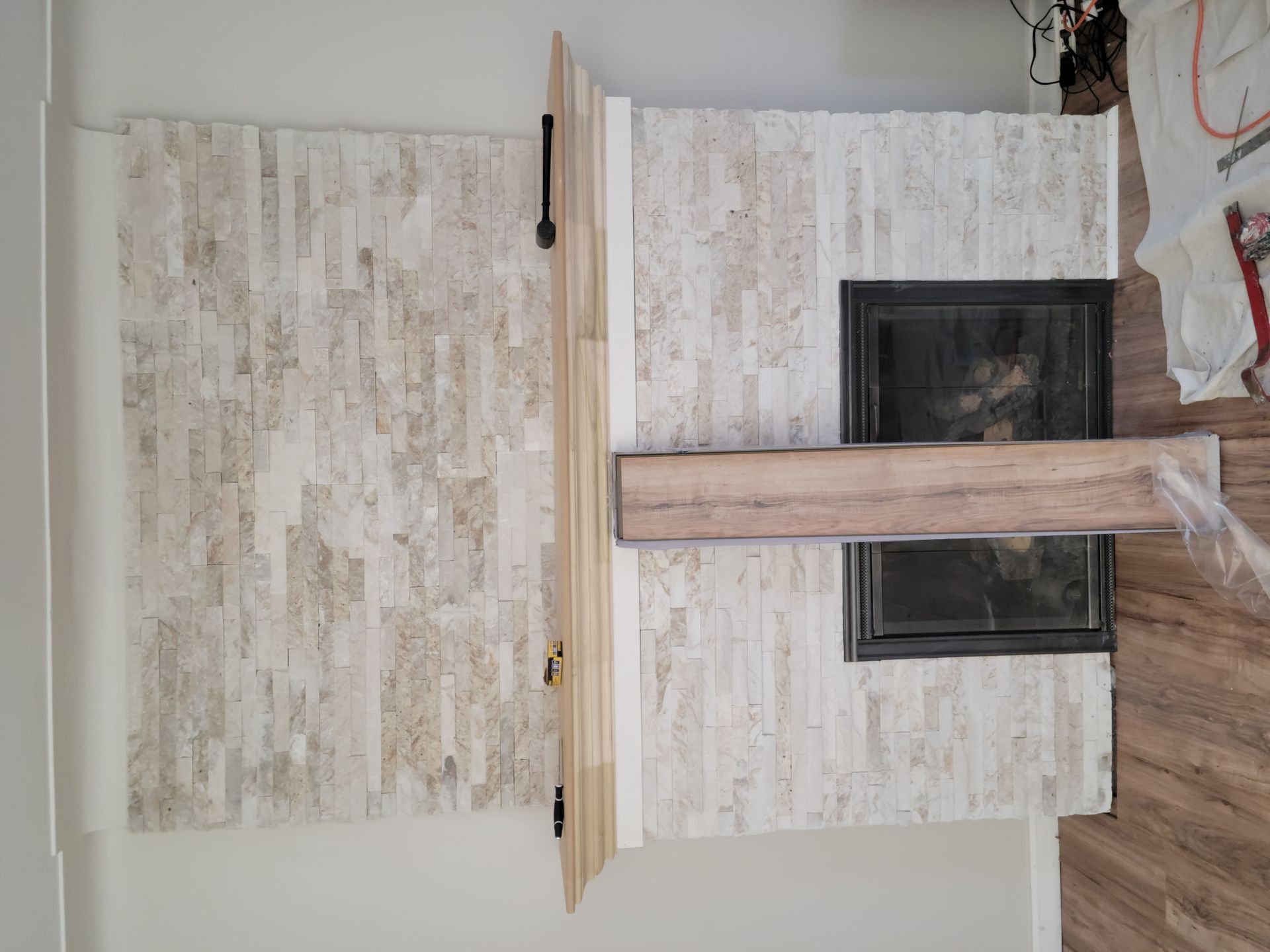 A fireplace with a wooden mantle is being built in a living room.