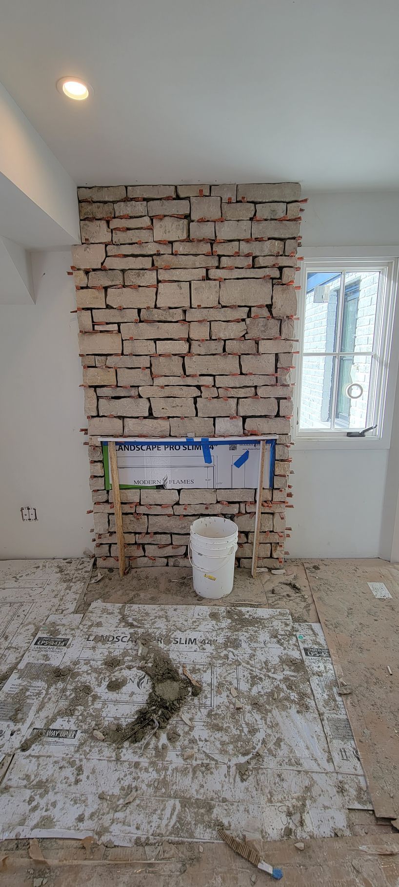 A brick fireplace is being built in a living room.