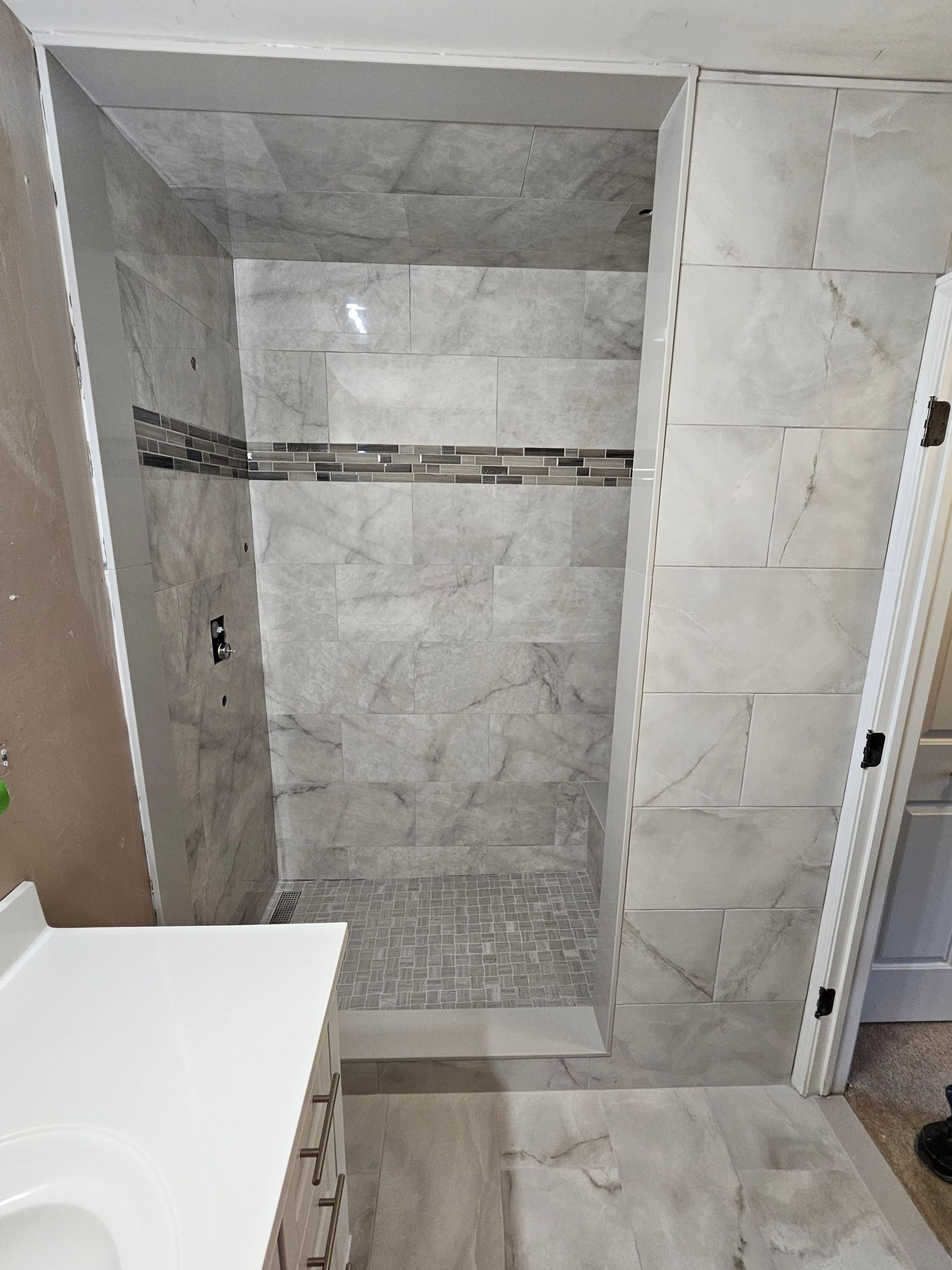 A bathroom with a walk in shower and a sink.