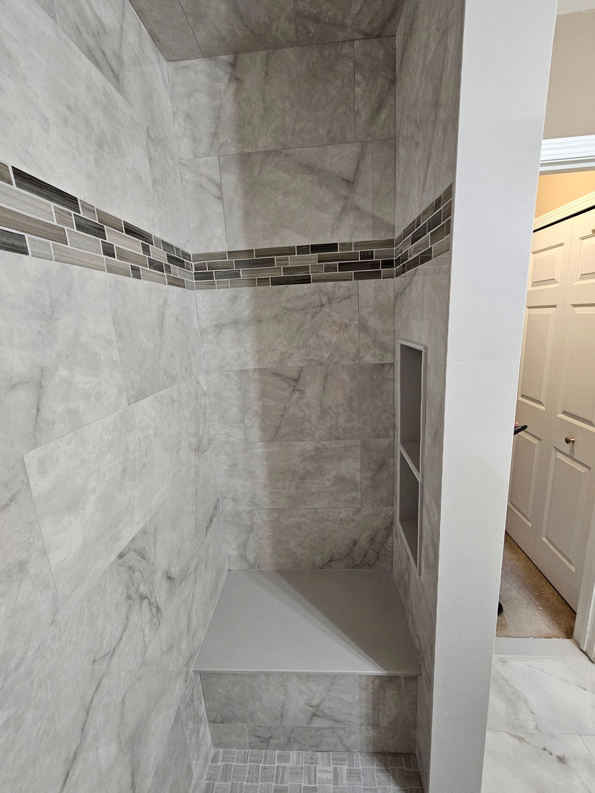 A bathroom with marble tiles and a walk in shower.