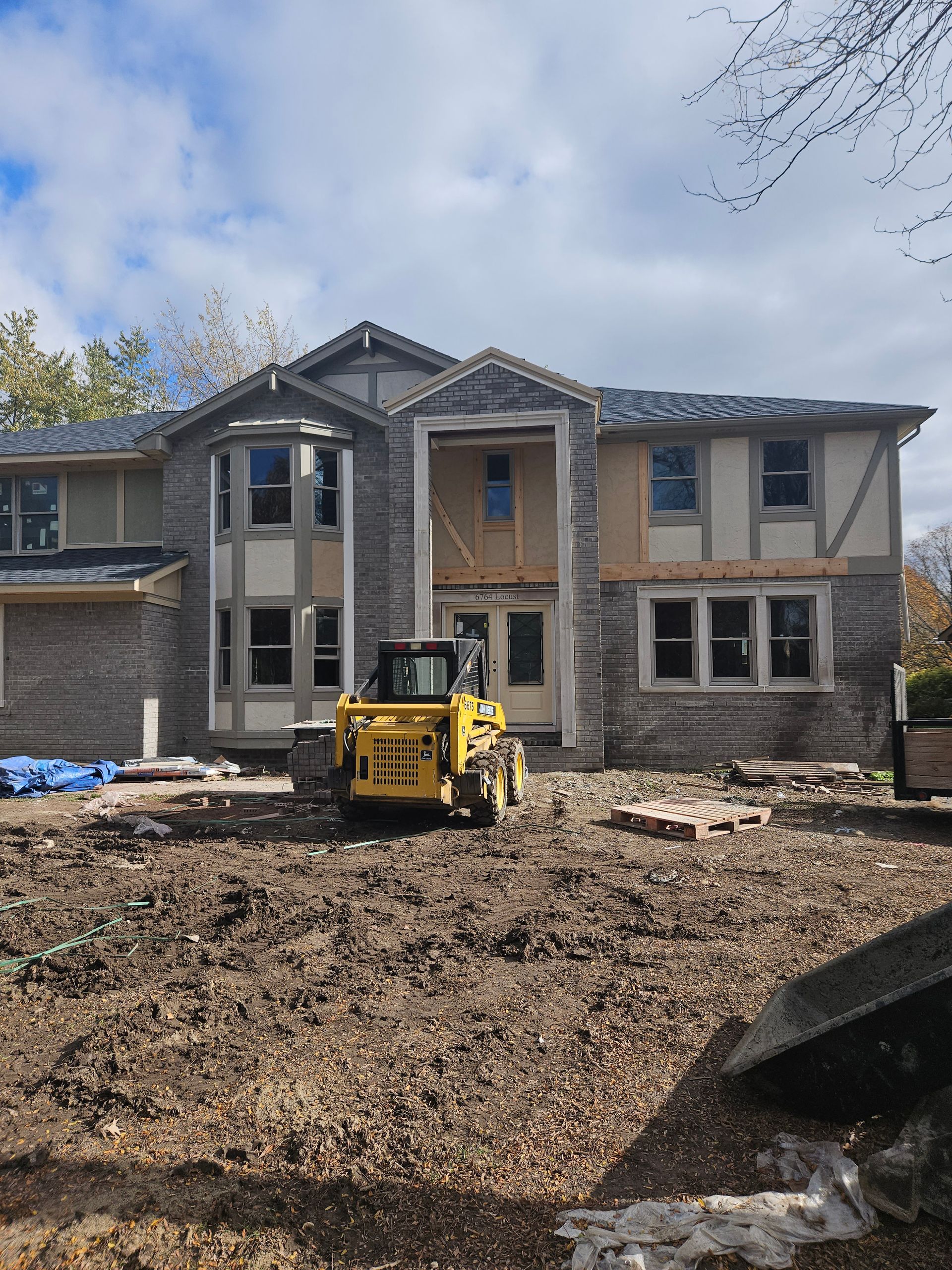 A large house under construction with a bulldozer in front of it