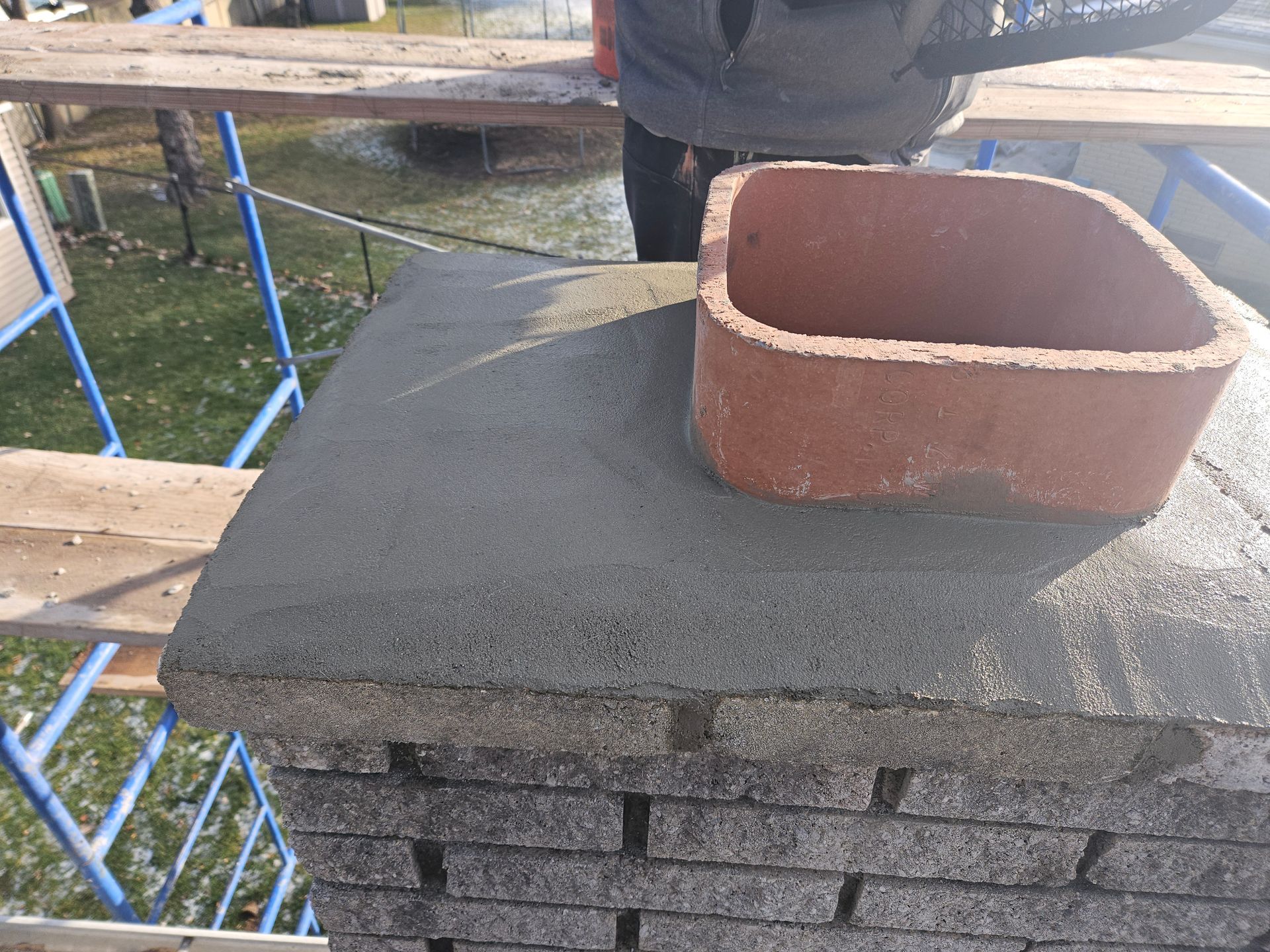 A man is working on a chimney with a brick chimney on top of it.