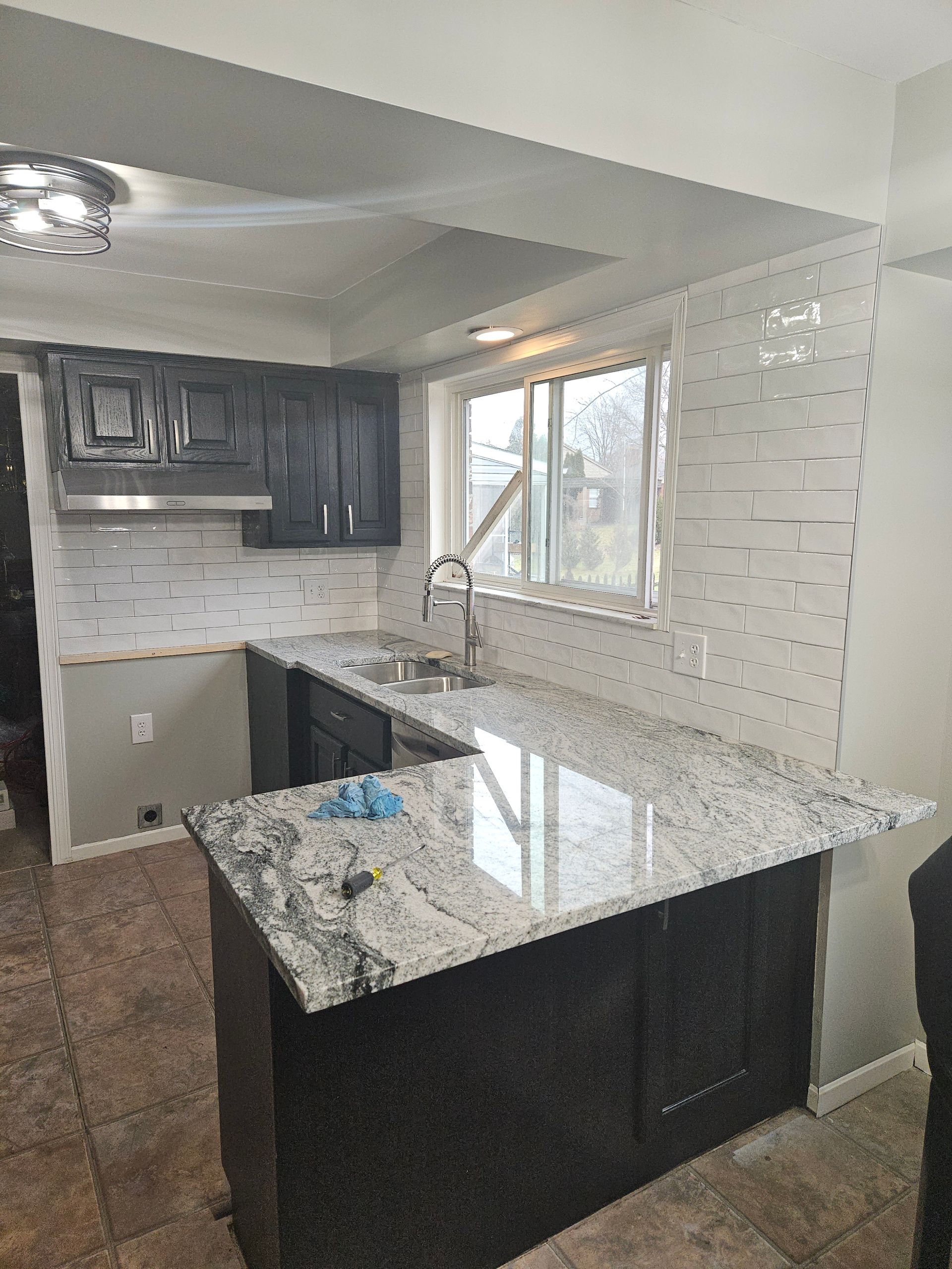 A kitchen with granite counter tops and black cabinets is being remodeled.