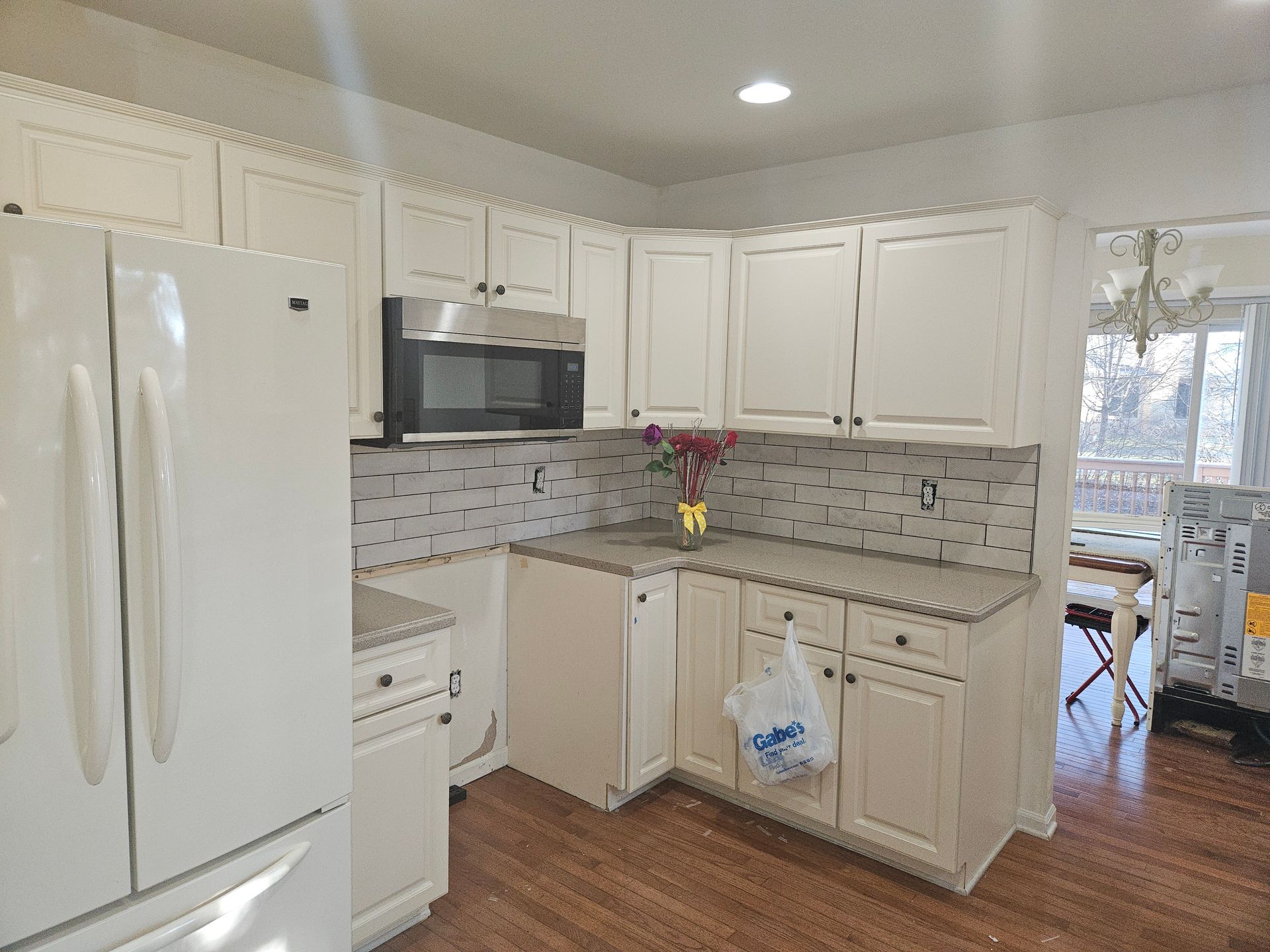 A kitchen with white cabinets , a refrigerator , a microwave , and a sink.