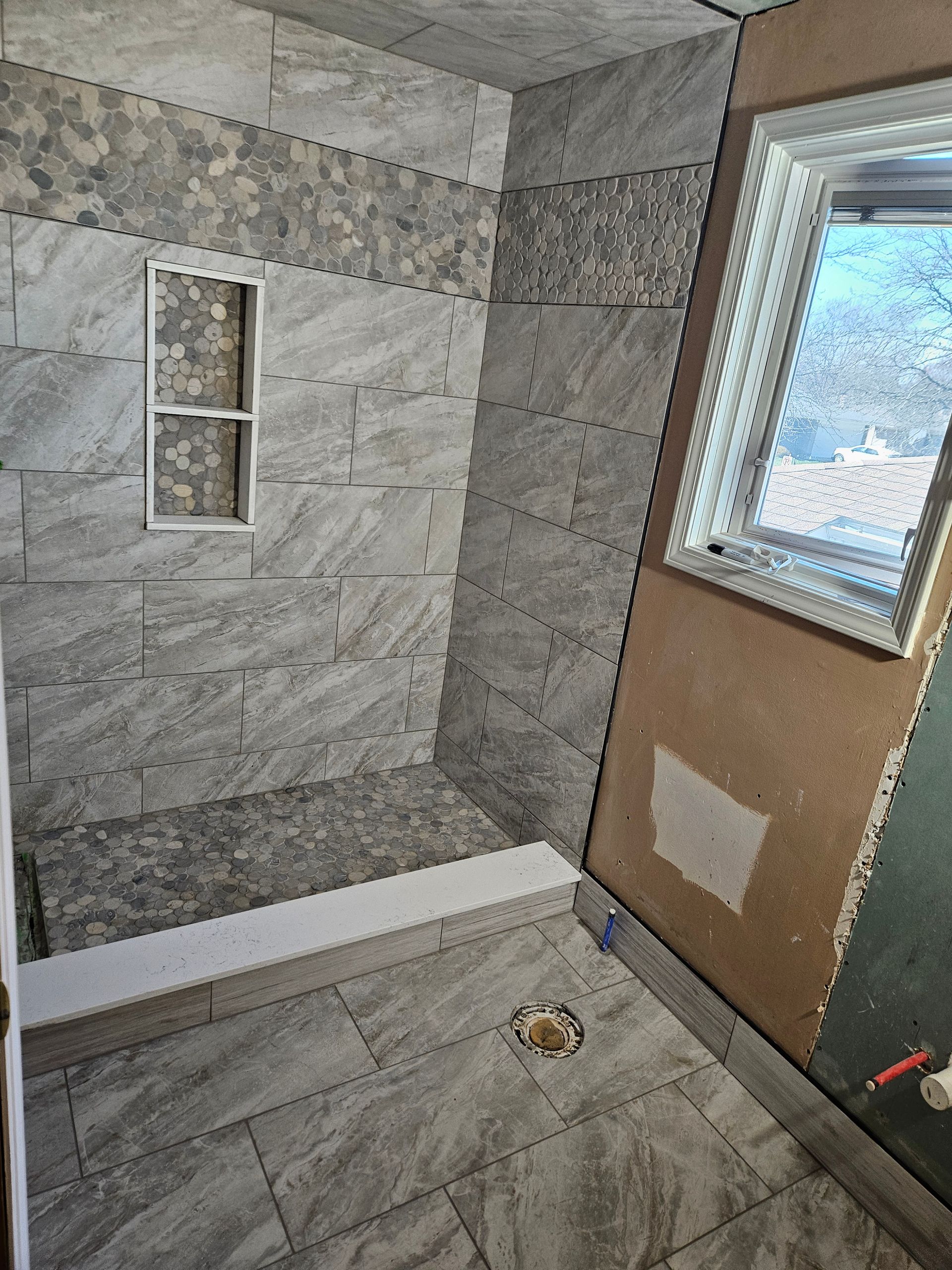 A bathroom with a walk in shower and a window.