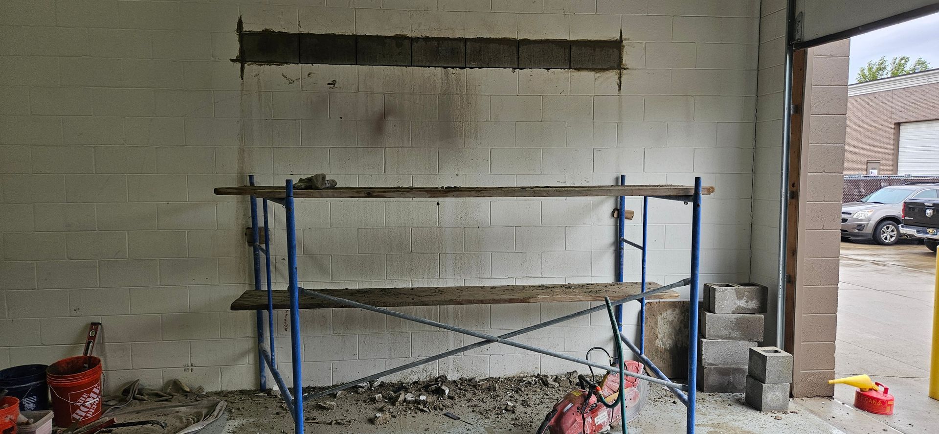 A blue scaffolding is sitting in front of a white brick wall.