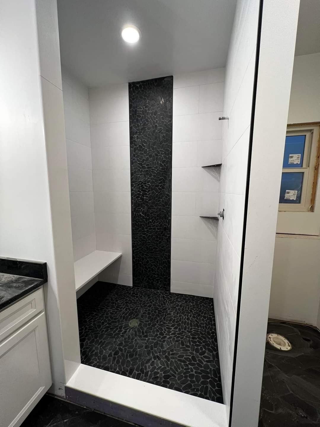 A bathroom with a walk in shower and a bench.
