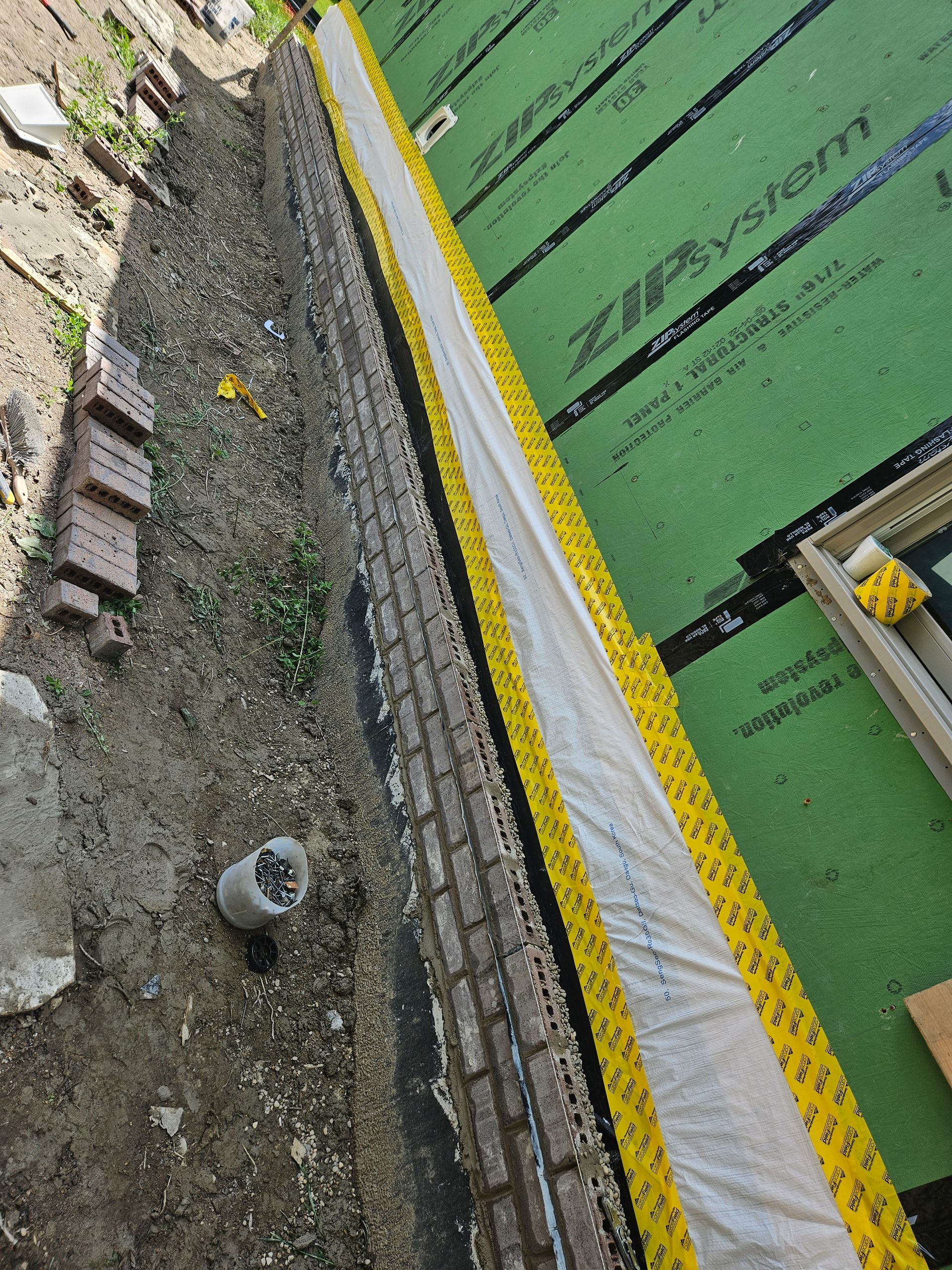 A brick wall is being covered with a green tarp that says zipvision