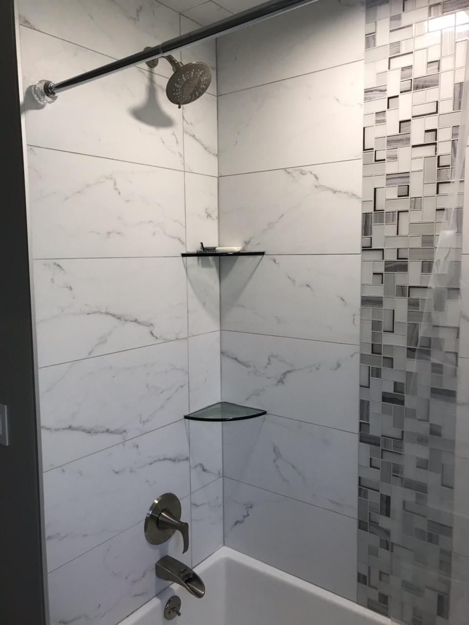 A bathroom with a tub , shower , and shelves.