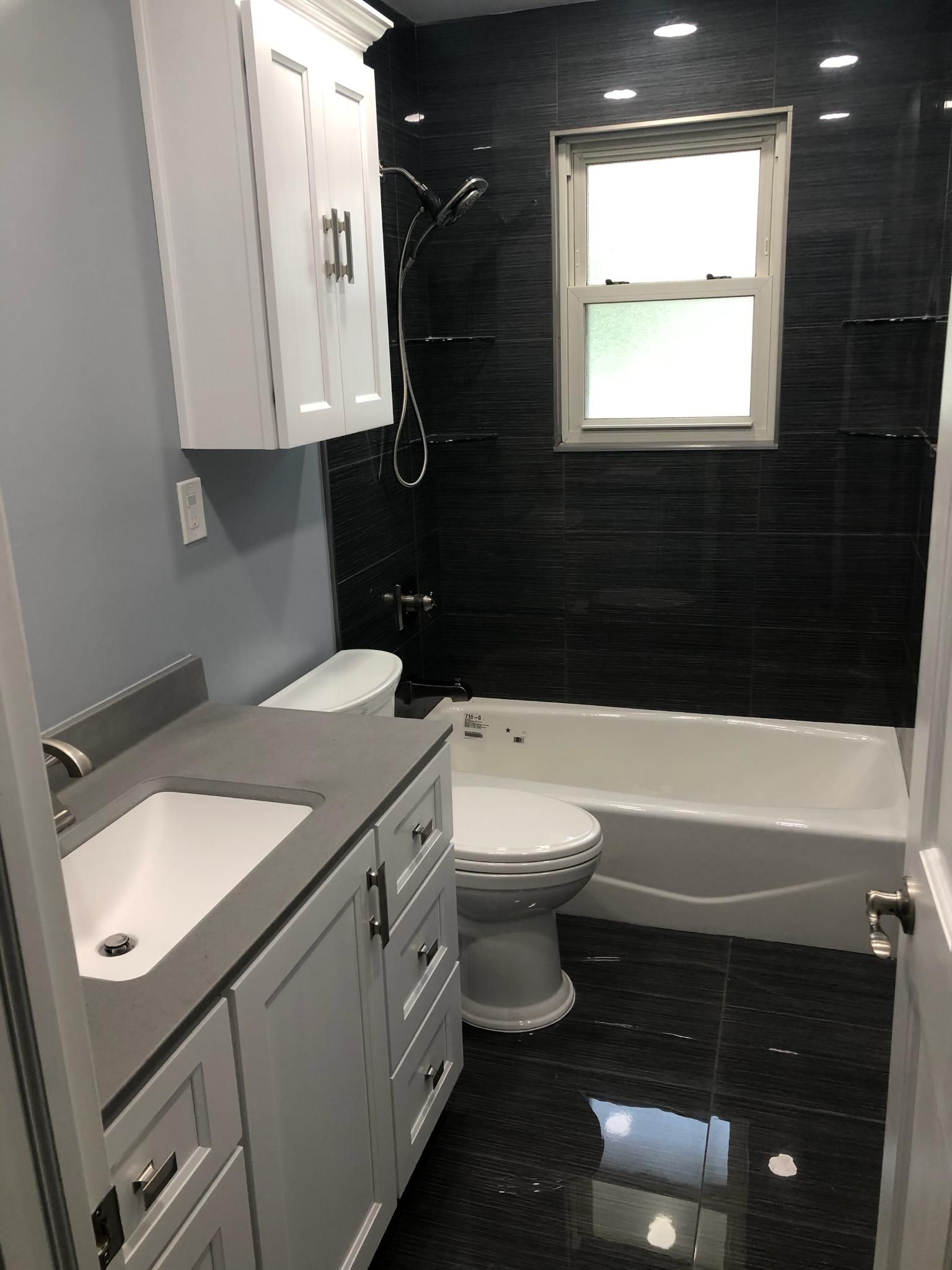 A bathroom with a toilet , sink , tub and window.