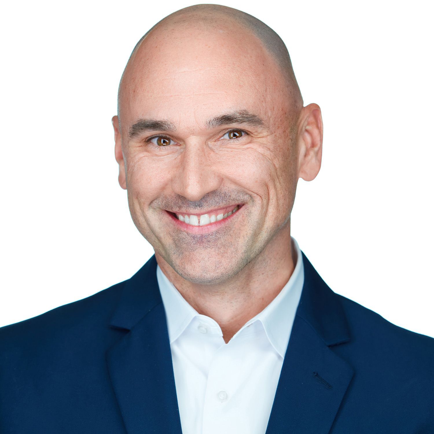 Bald man wearing a blue blazer and white shirt, smiling, looking at the camera.