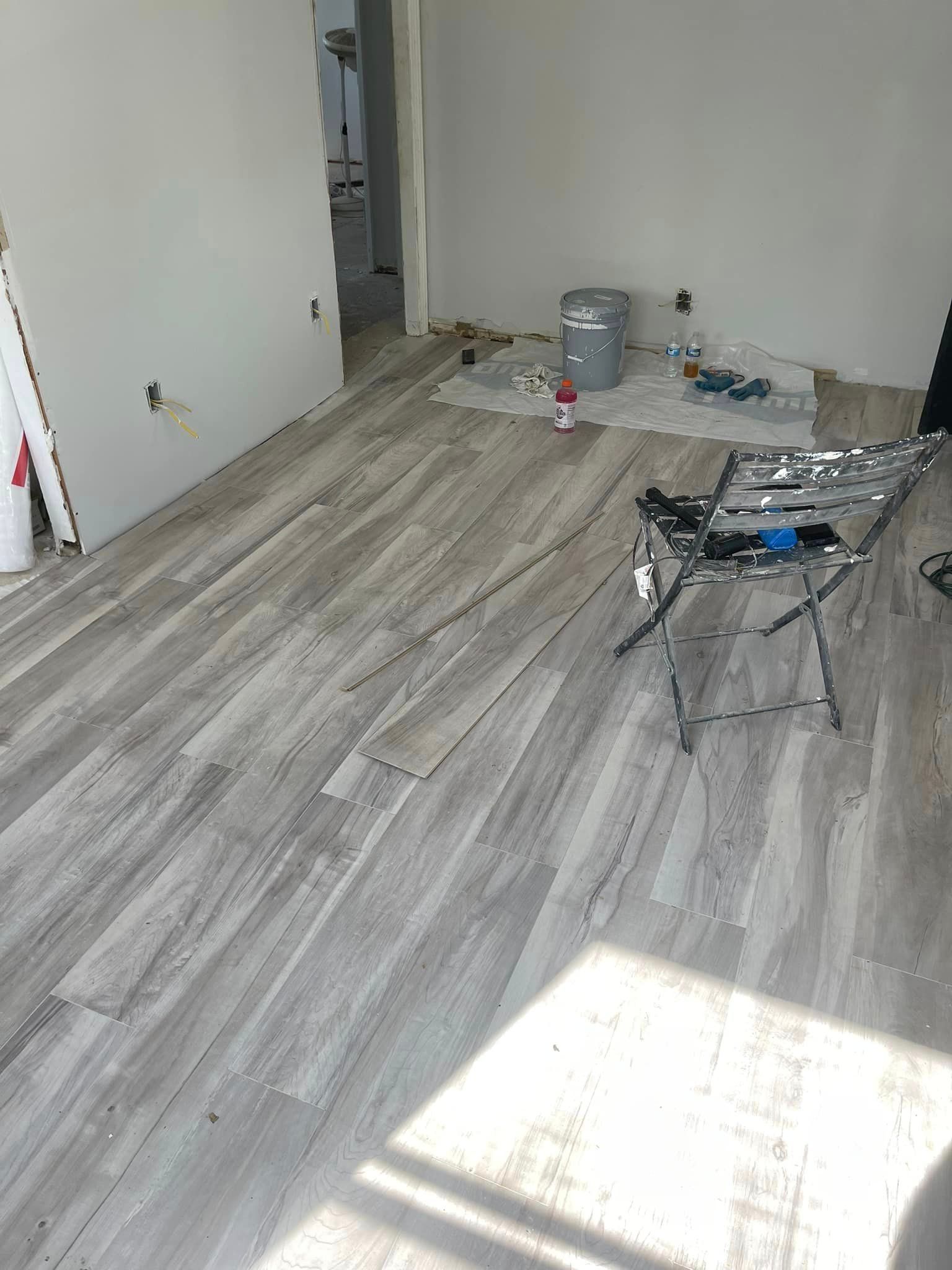 A room with a wooden floor and white walls is being painted.