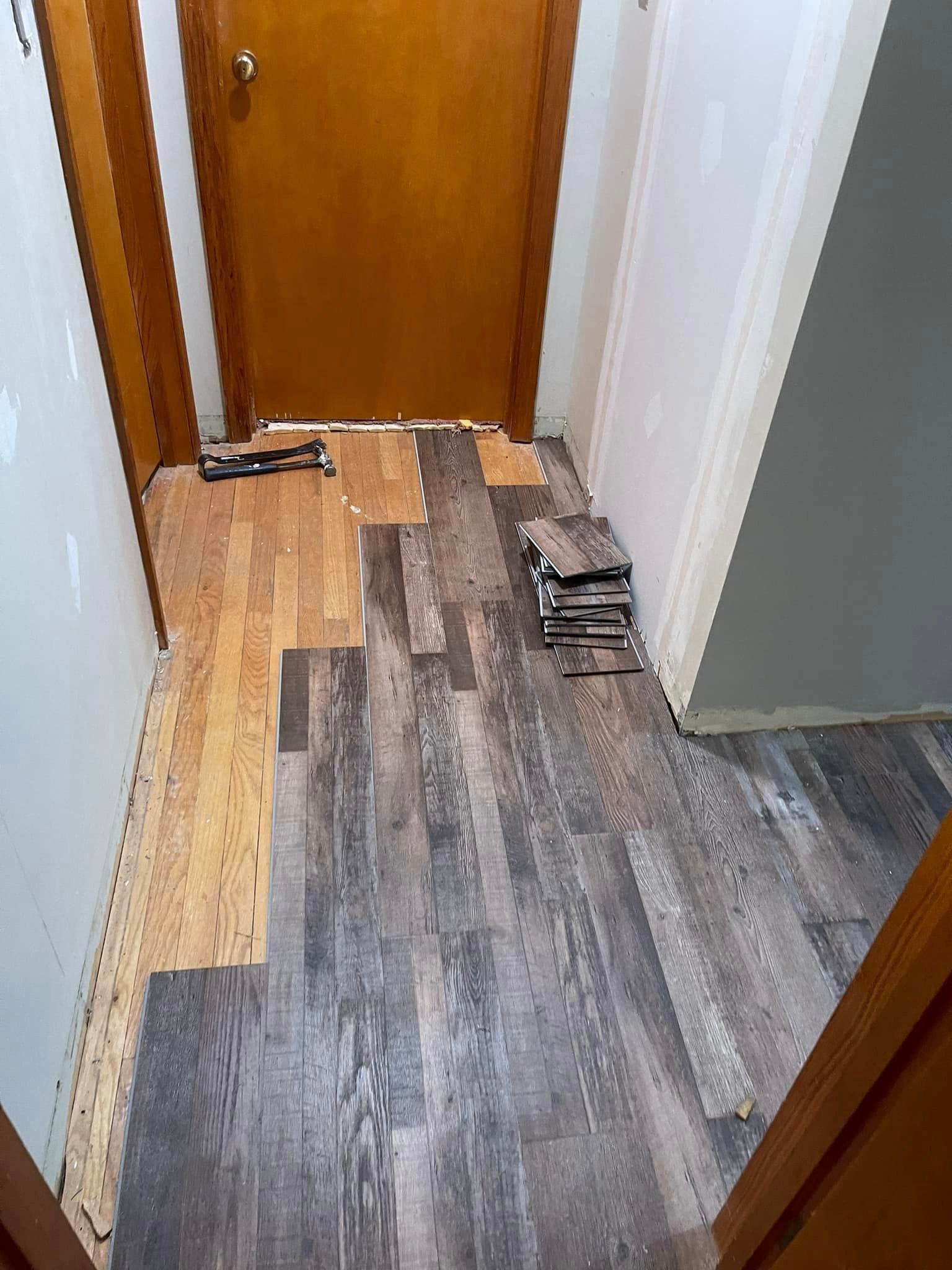 A hallway with a wooden floor and a door.