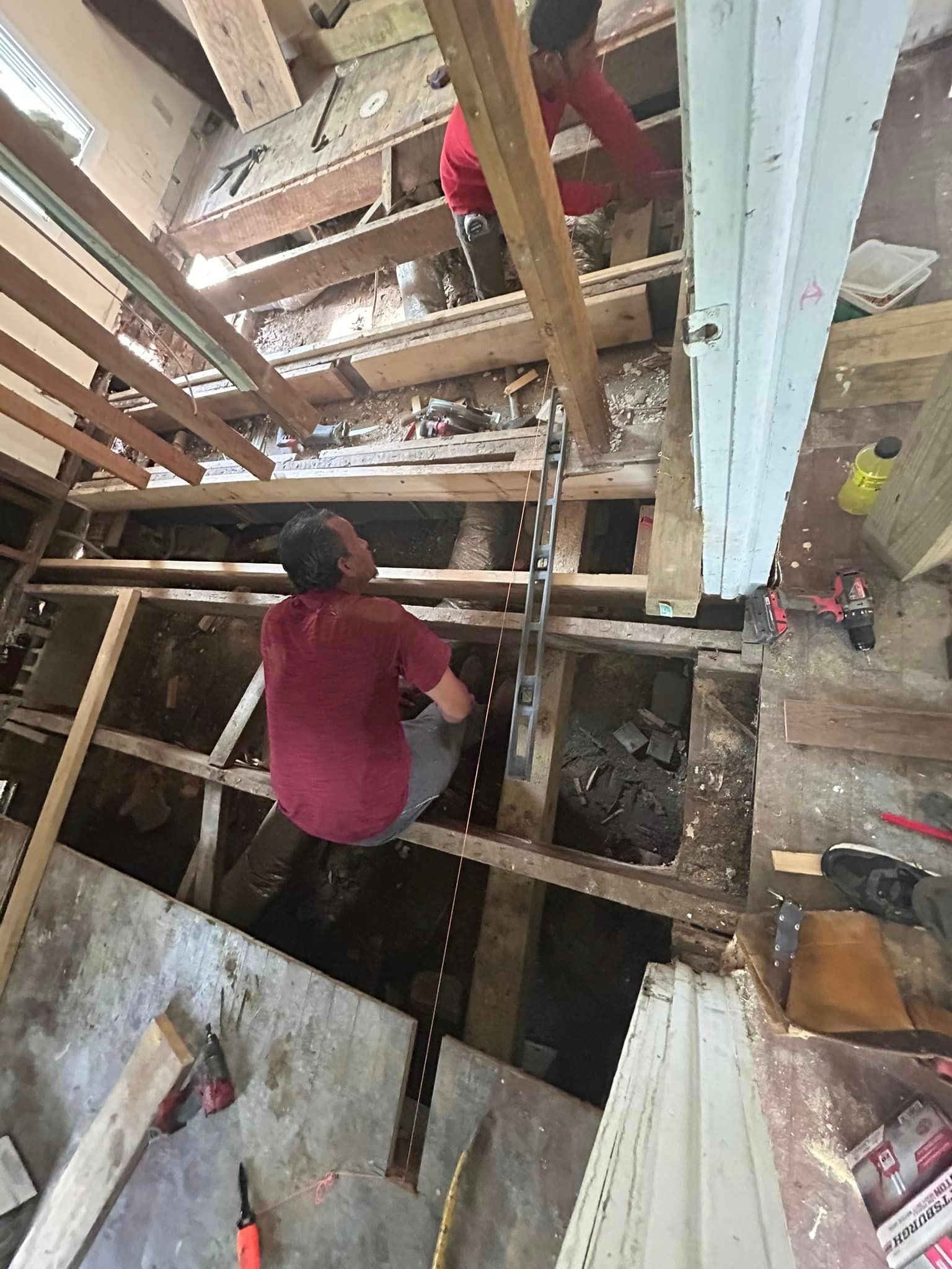 A man is working on a wooden floor in a room.