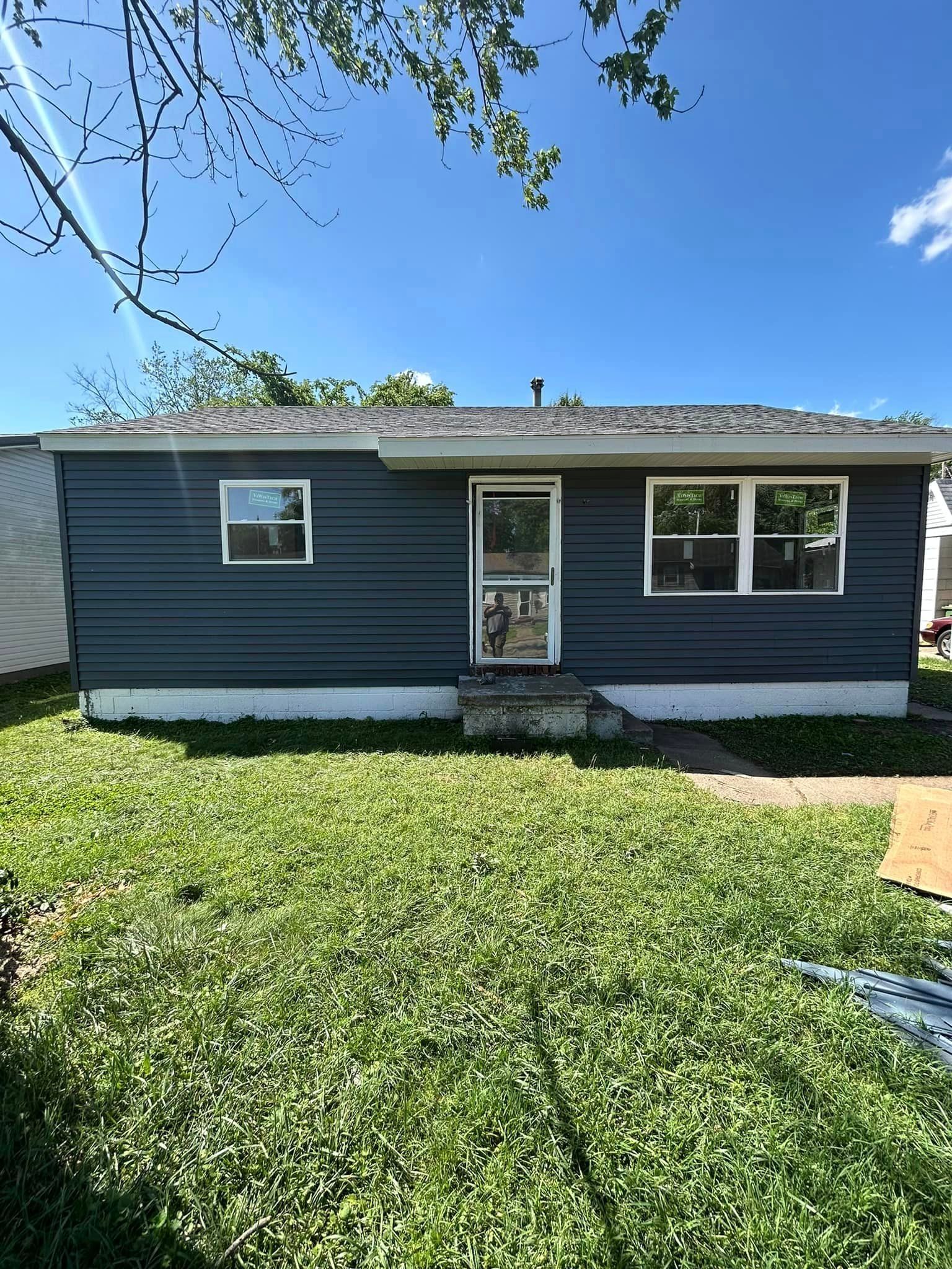A small house with a lot of windows is sitting on top of a lush green lawn.