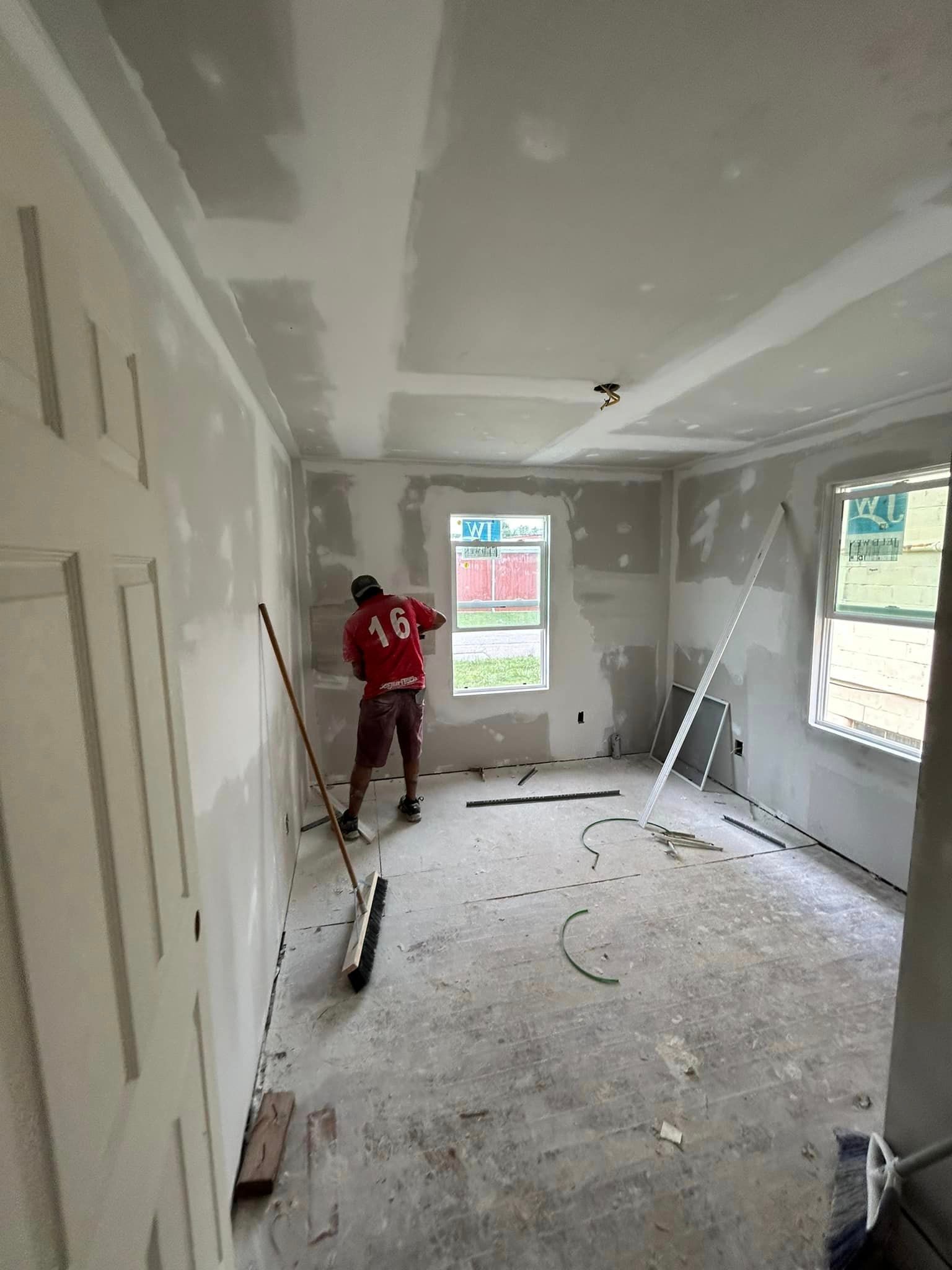 A man is standing in a room with a broom.