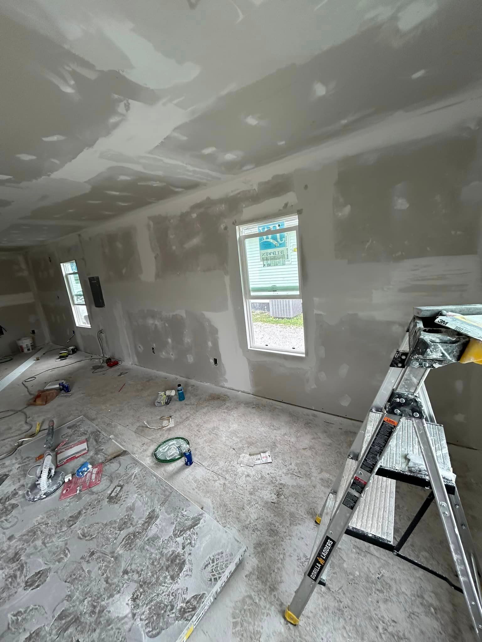 A room with drywall and a ladder in it.